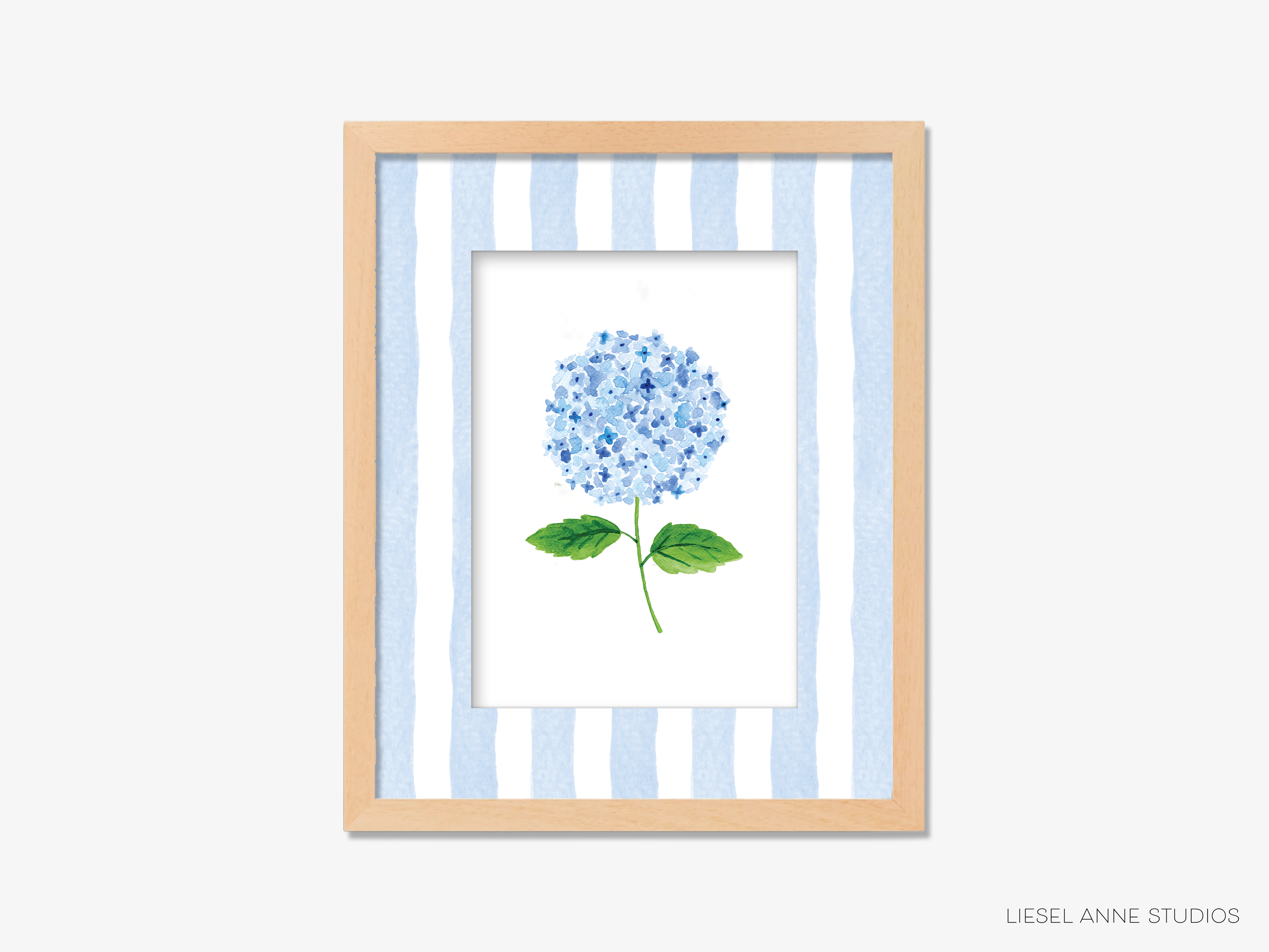A framed print of a blue hydrangea flower with green leaves, set against a striped blue and white background.