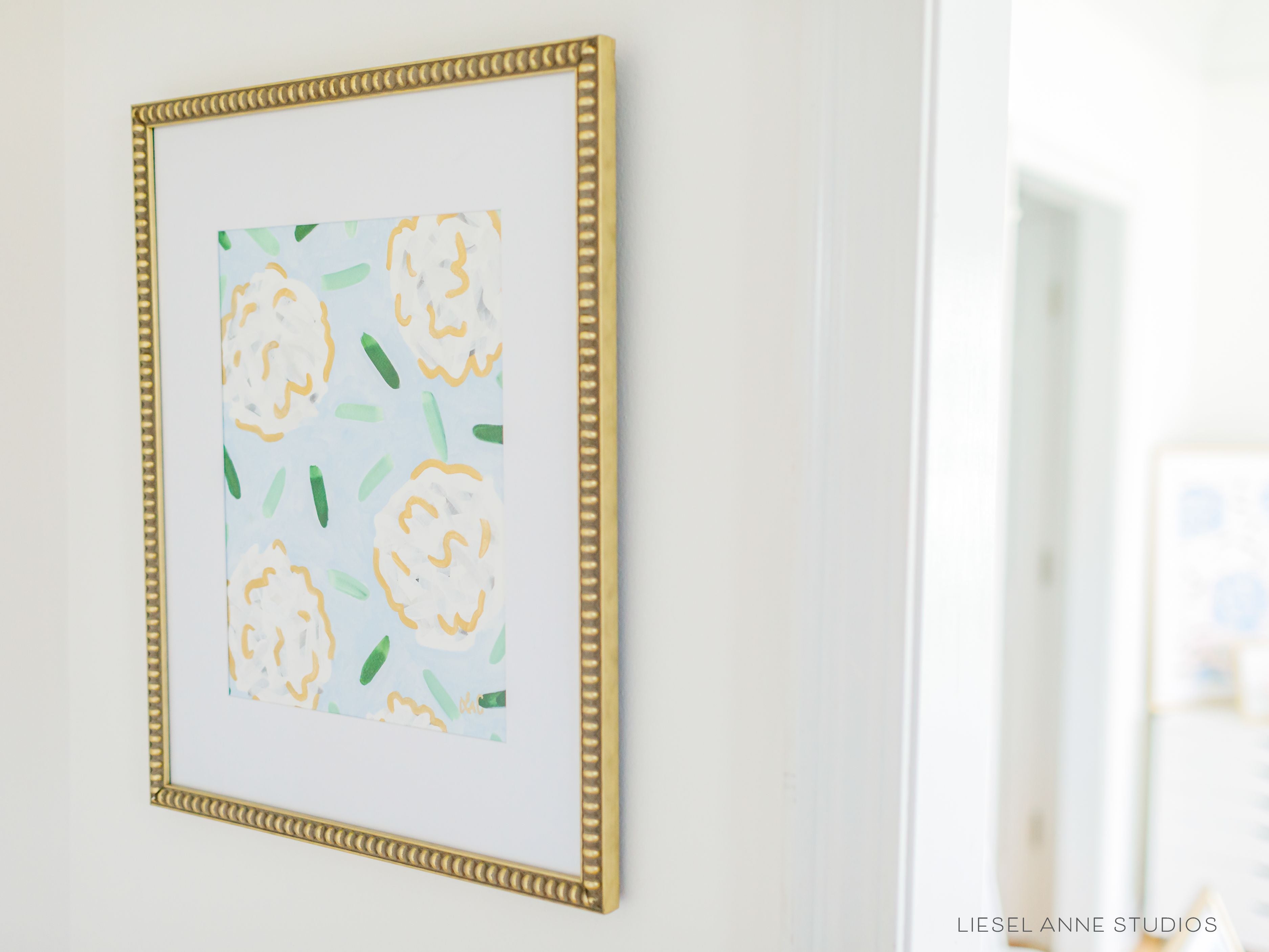 Golden Hydrangea | Blue & White V-Original artwork measures 11"x14" | Hand-Painted with gouache on cold press watercolor paper | Matted and framed in gold wood frame sized 16"x20" | Glare-resistant glass | Hanging hardware included | Features our signature Golden Hydrangea design with a light blue base, white hydrangeas and shimmery gold accents | Initialed in gold by the Liesel Anne (the artist) on the front and signed and dated on the back.-The Singing Little Bird