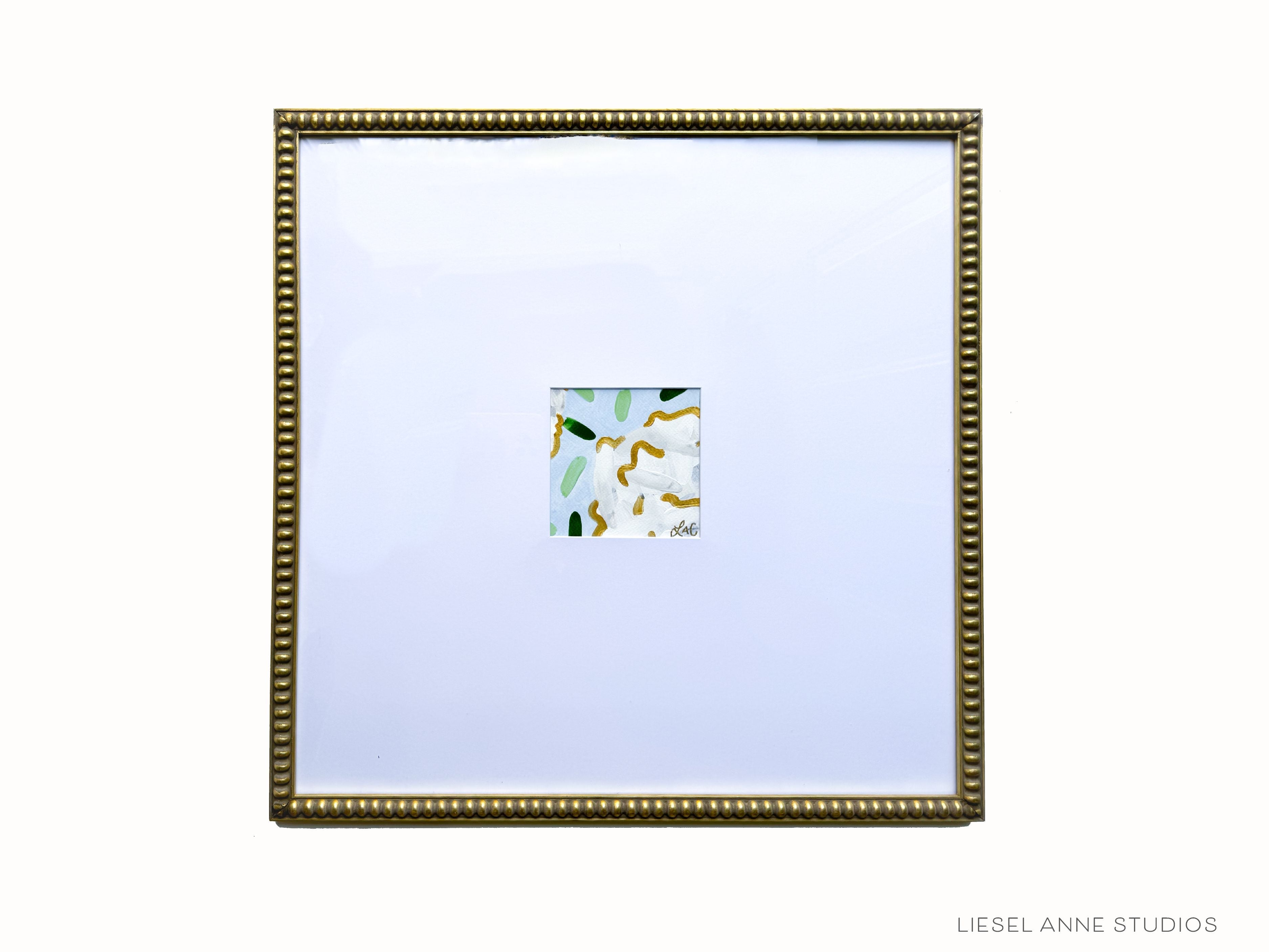 Golden Hydrangea Mini (Oversized Frame) | Blue & White XIX-Original artwork measures 5"x5" | Hand-Painted with gouache on cold press watercolor paper | Matted and framed in gold wood frame sized 20"x20" | Glare-resistant glass | Hanging hardware included | Features our signature Golden Hydrangea design with a light blue base, white hydrangeas and shimmery gold accents | Initialed in gold by the Liesel Anne (the artist) on the front and signed and dated on the back.-The Singing Little Bird