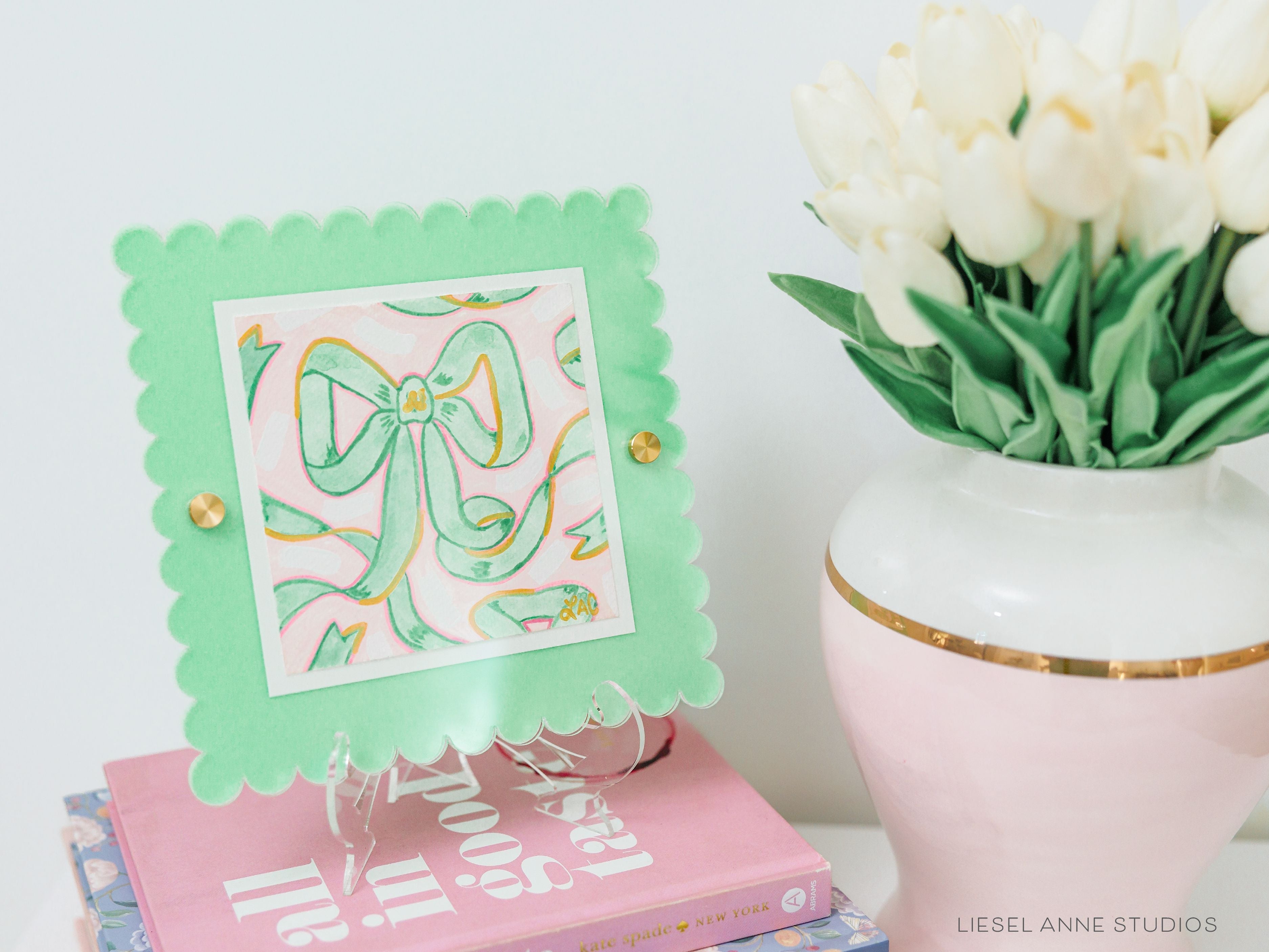 Pink & Green Golden Bows Art Print [5x5]-Art Print measures 5"x5" | Optional coordinating frame add on with hanging hardware and acrylic clear stand included | Features our signature Golden Bows design with a light pink base, light green bows and hand painted shimmery gold embellishments | Initialed in gold by Liesel Anne (the artist) on the front and signed and dated on the back-The Singing Little Bird