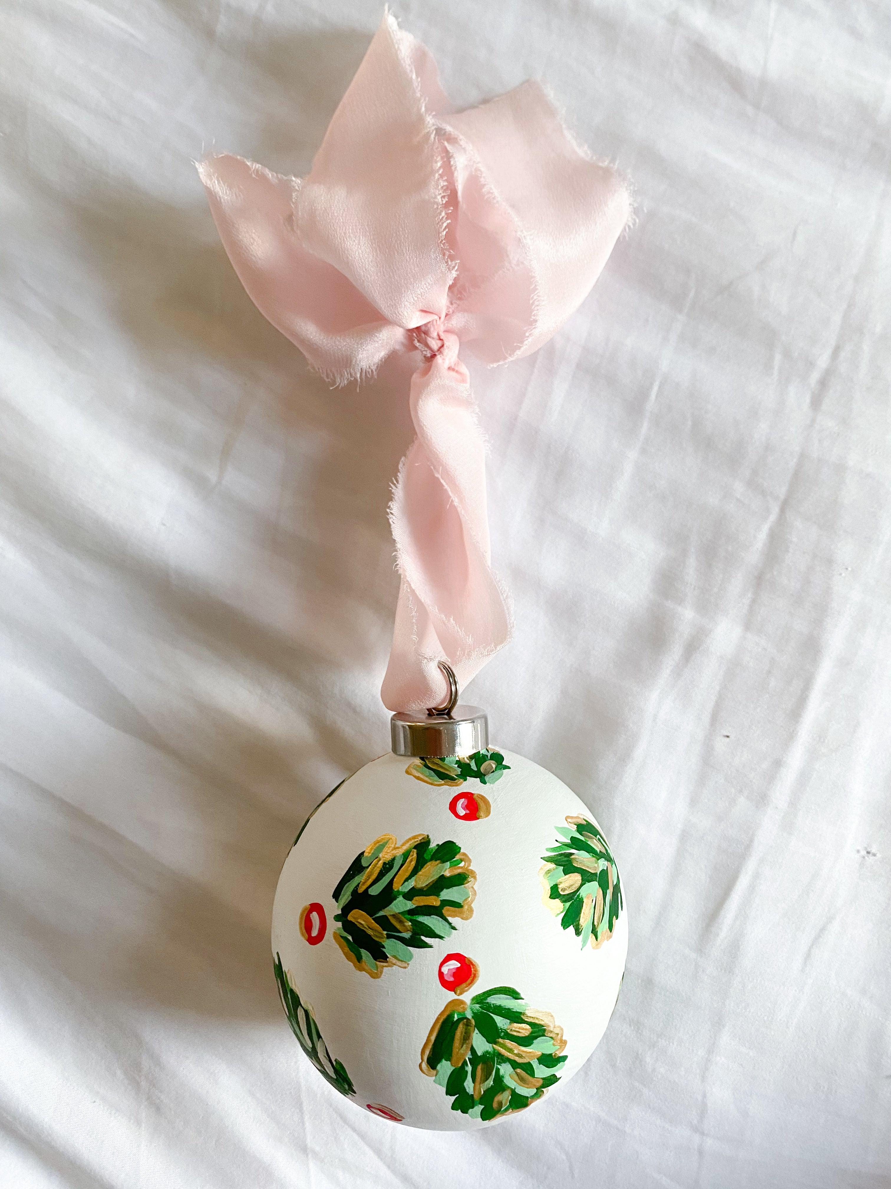 Winter Pearl Golden Holly Bauble-Ceramic Hand-Painted Keepsake Ornament | Measuring 3" x 3" | Features the Golden Holly design with an ivory base and shimmery gold accents | Coated with a protective matte finish that will keep it protected and shimmering year after year | Your color choice of silk crepe ribbon with a frayed edge for hanging | Each bauble is slightly different with potential small imperfections due to the hand-painted nature, making each one special and unique!-The Singing Little Bird