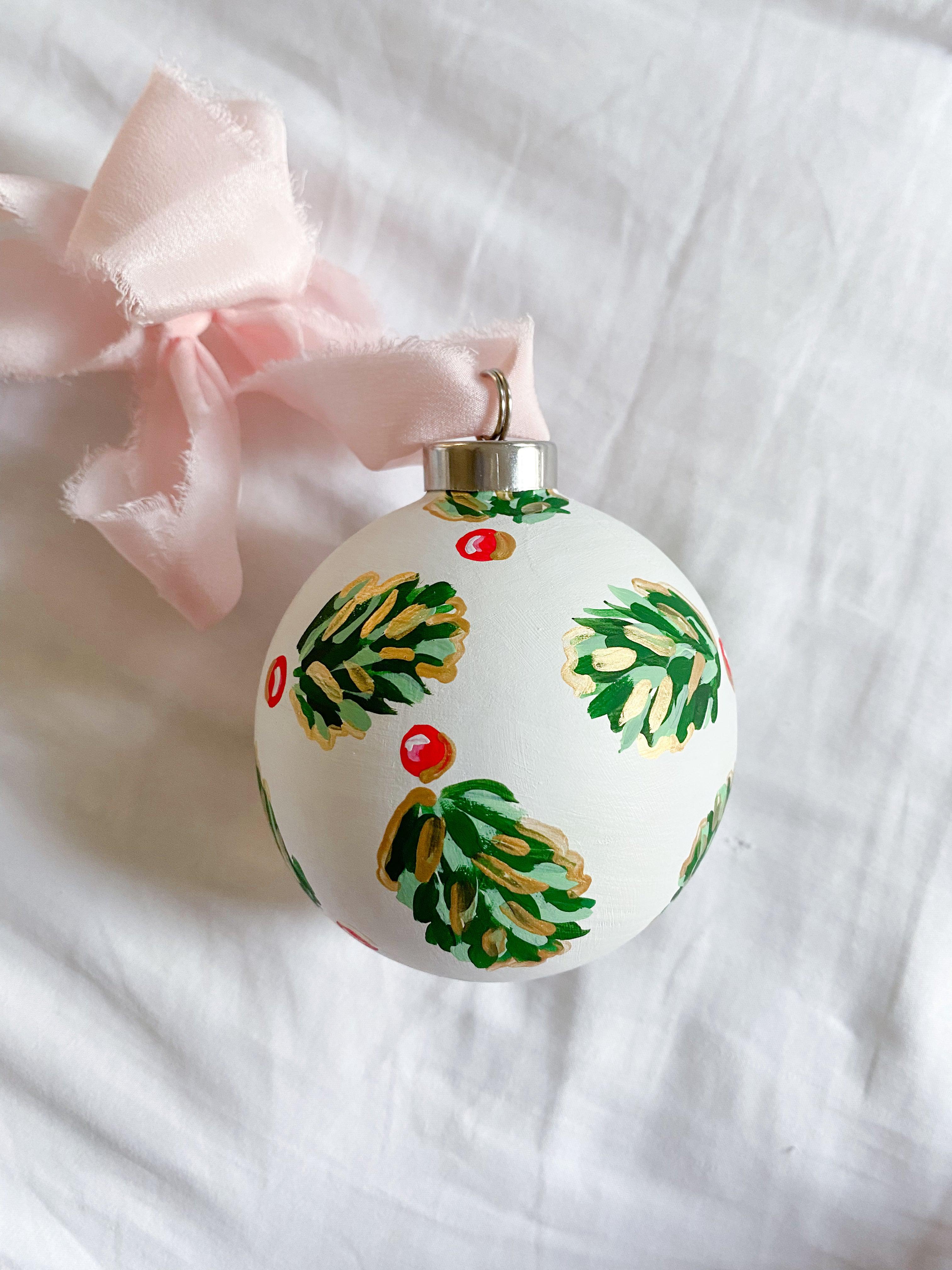 Winter Pearl Golden Holly Bauble-Ceramic Hand-Painted Keepsake Ornament | Measuring 3" x 3" | Features the Golden Holly design with an ivory base and shimmery gold accents | Coated with a protective matte finish that will keep it protected and shimmering year after year | Your color choice of silk crepe ribbon with a frayed edge for hanging | Each bauble is slightly different with potential small imperfections due to the hand-painted nature, making each one special and unique!-The Singing Little Bird