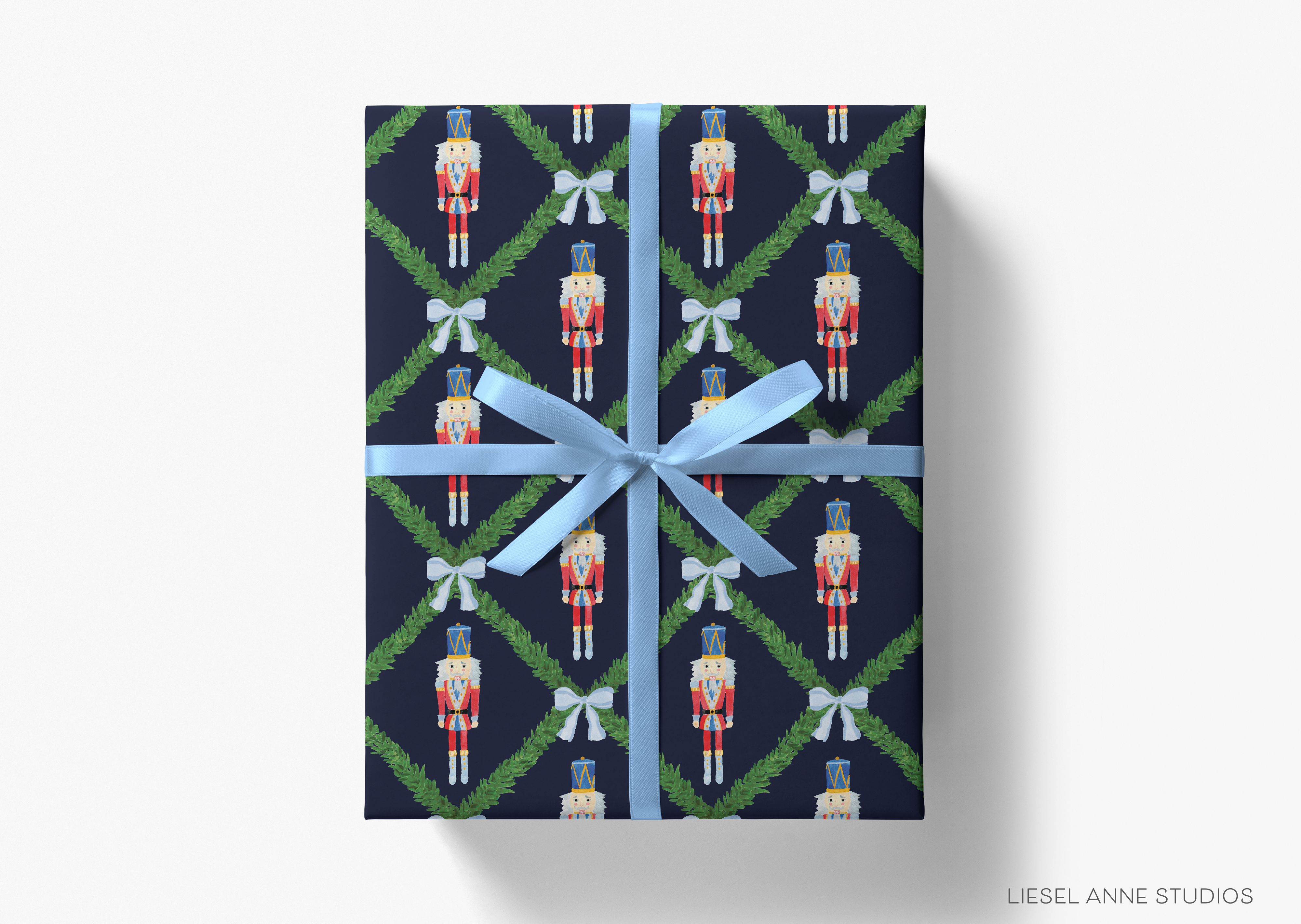 A gift box wrapped in a pattern of nutcracker figures and green leaves, tied with a blue ribbon.