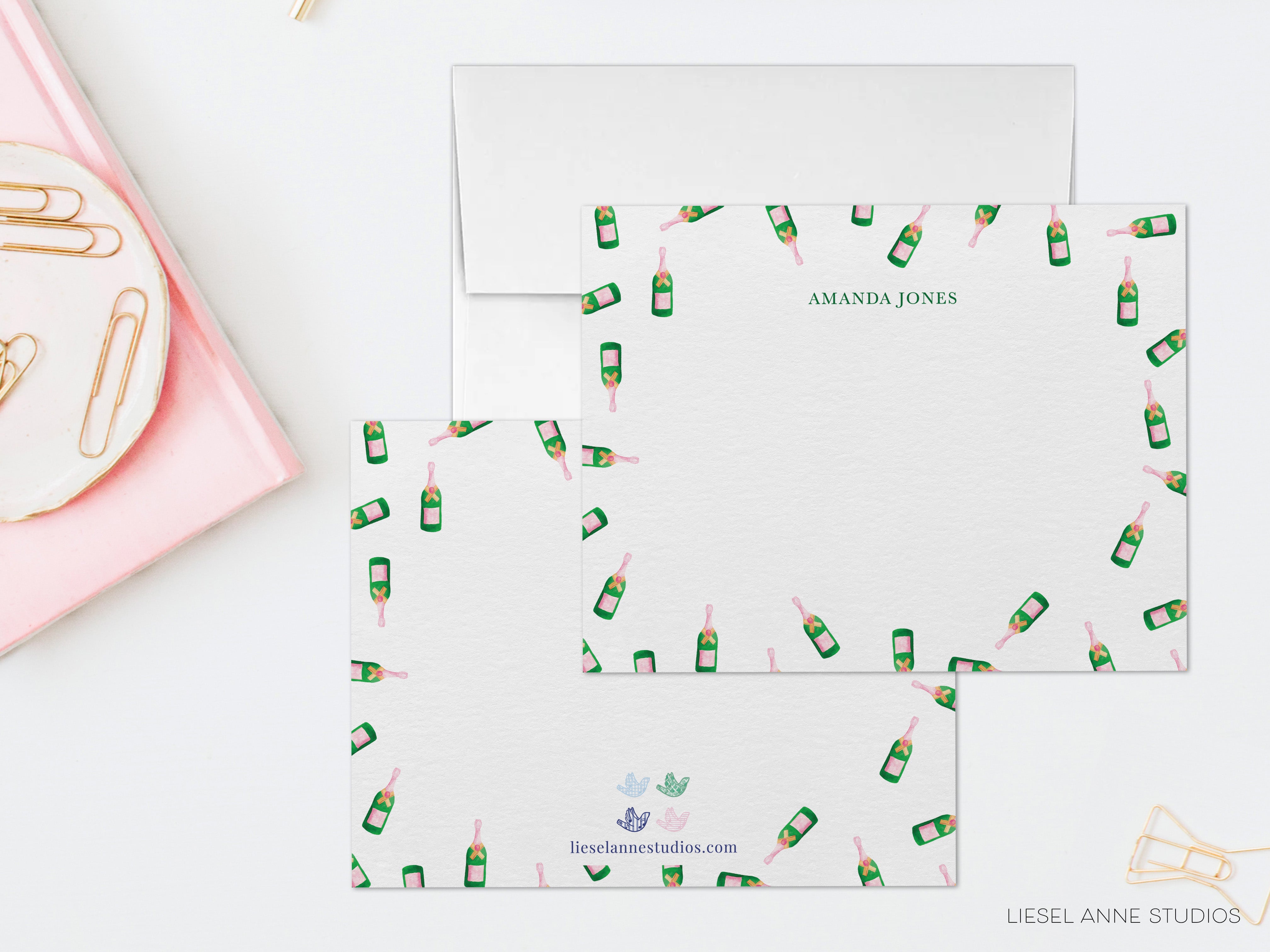 a set of personalized stationery items, including an envelope and a note card, with a pink background and a repeating pattern of champagne bottles.