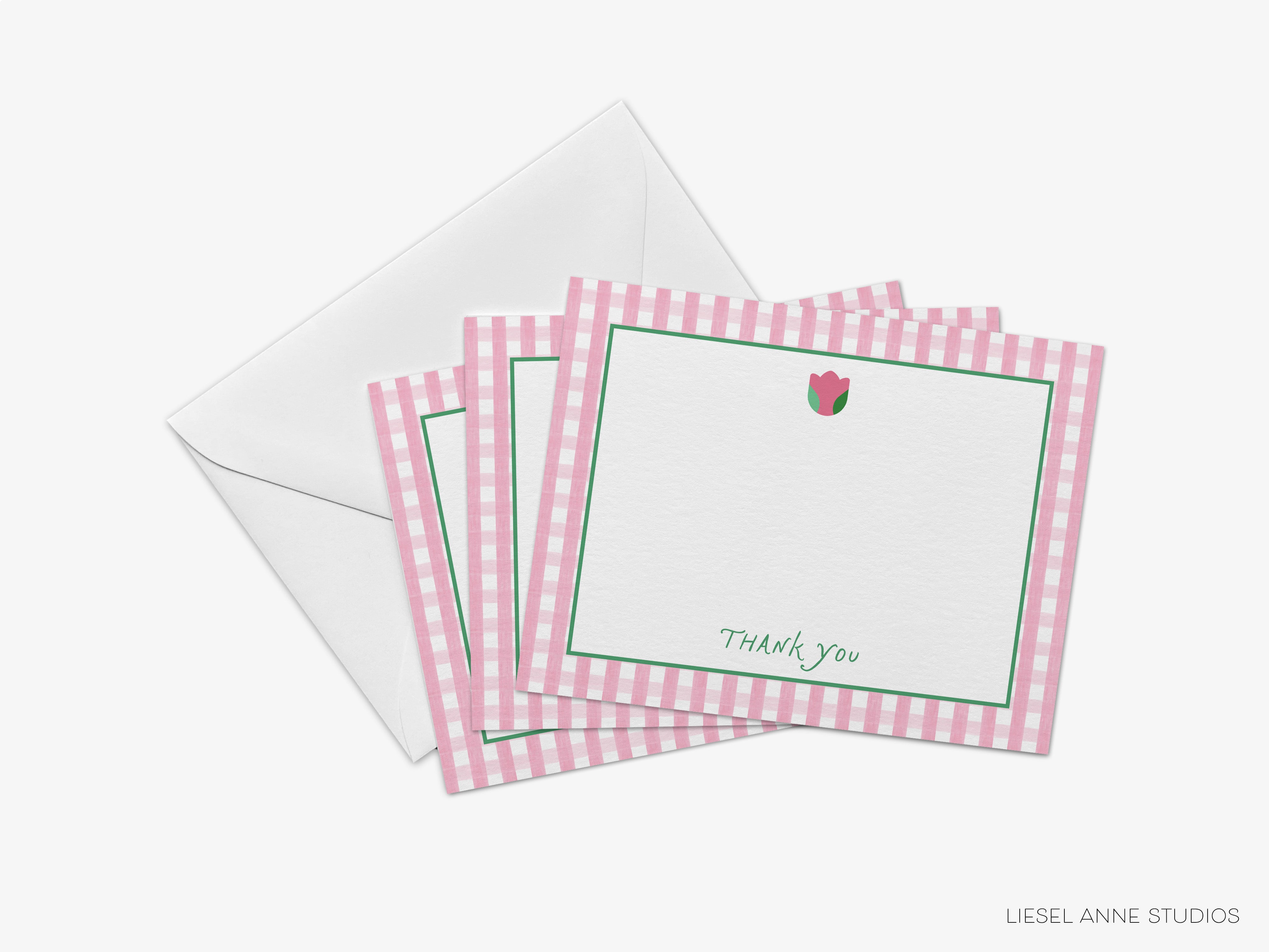 A set of pink and white checkered postcards with a blank space for a message, placed next to an envelope.