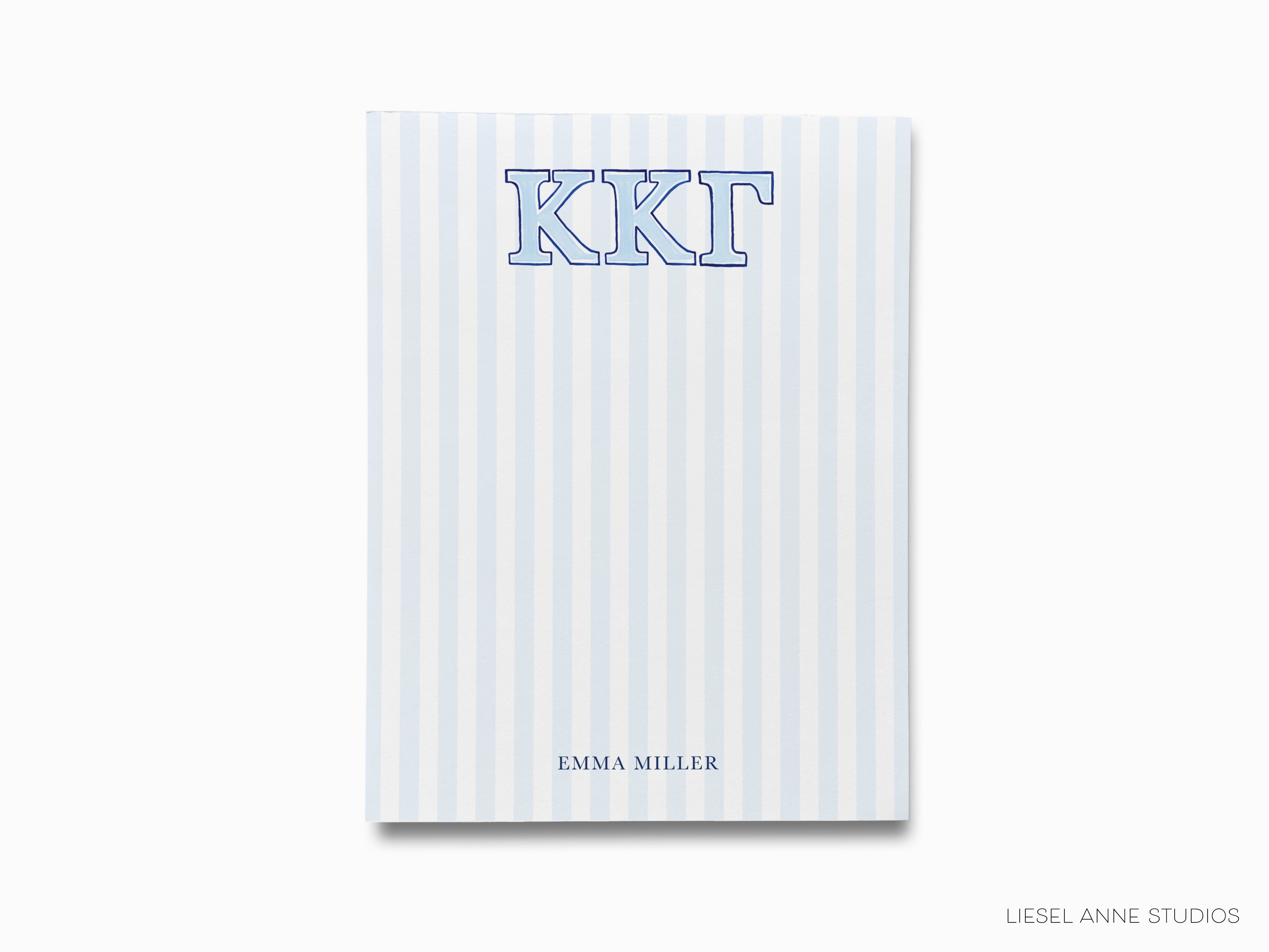 a blue and white striped notebook with the letter kkt on it