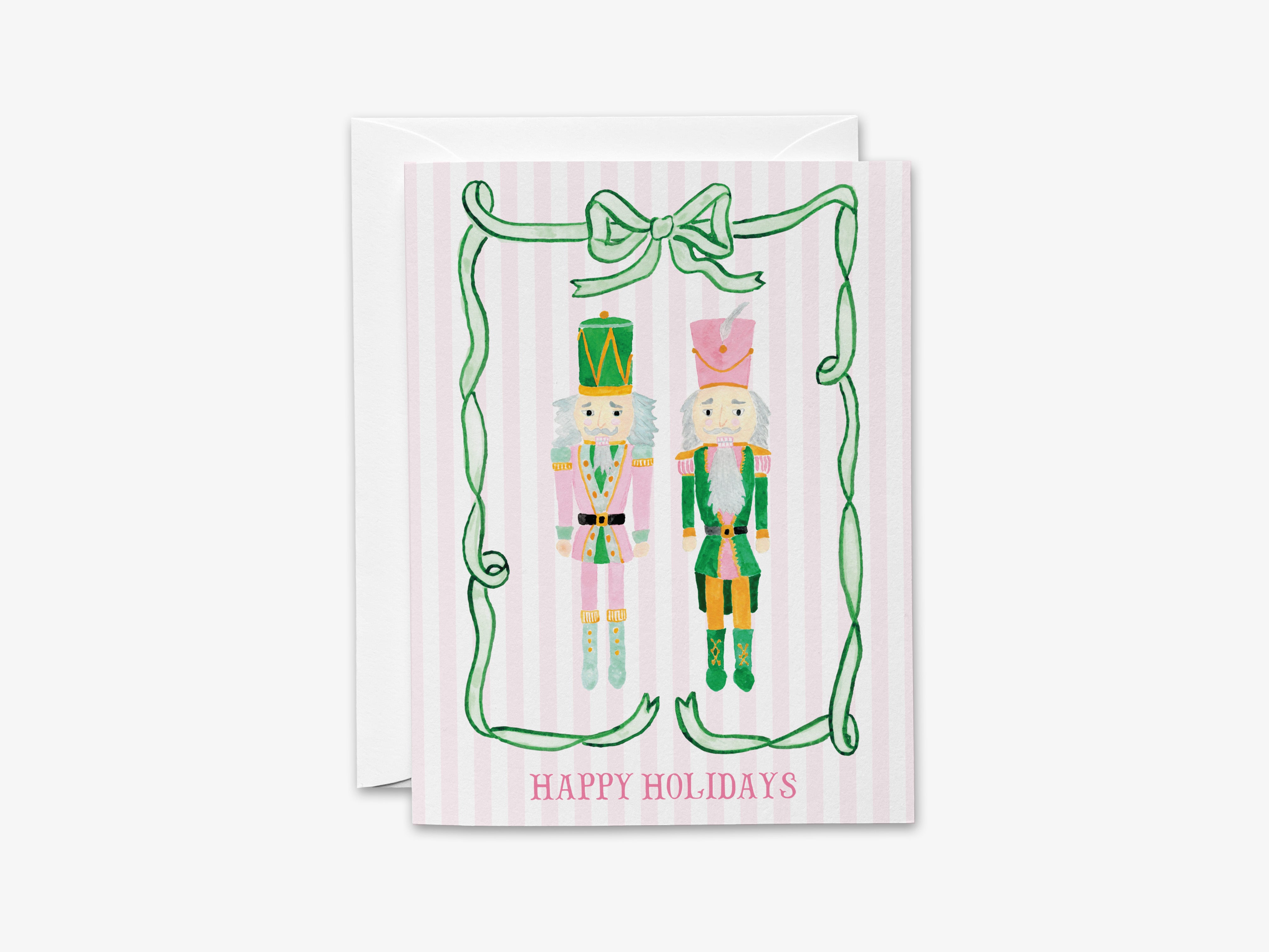A greeting card featuring two nutcracker characters, one in pink and one in green, standing in front of a green bow and the text "Happy Holidays".