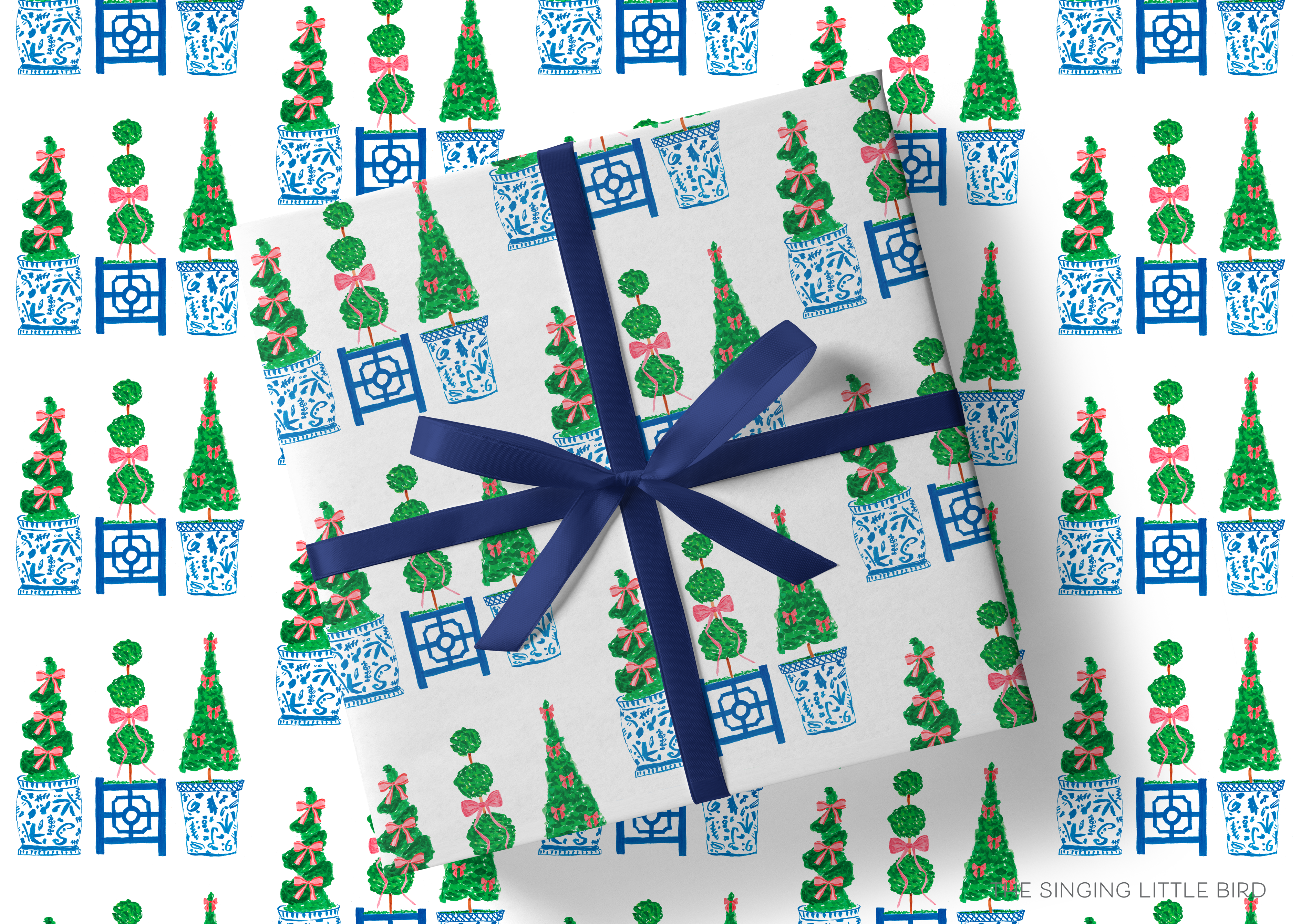 a gift wrapped in a white paper with a blue ribbon, adorned with a repeating pattern of green and blue Christmas trees and blue and white porcelain pots.