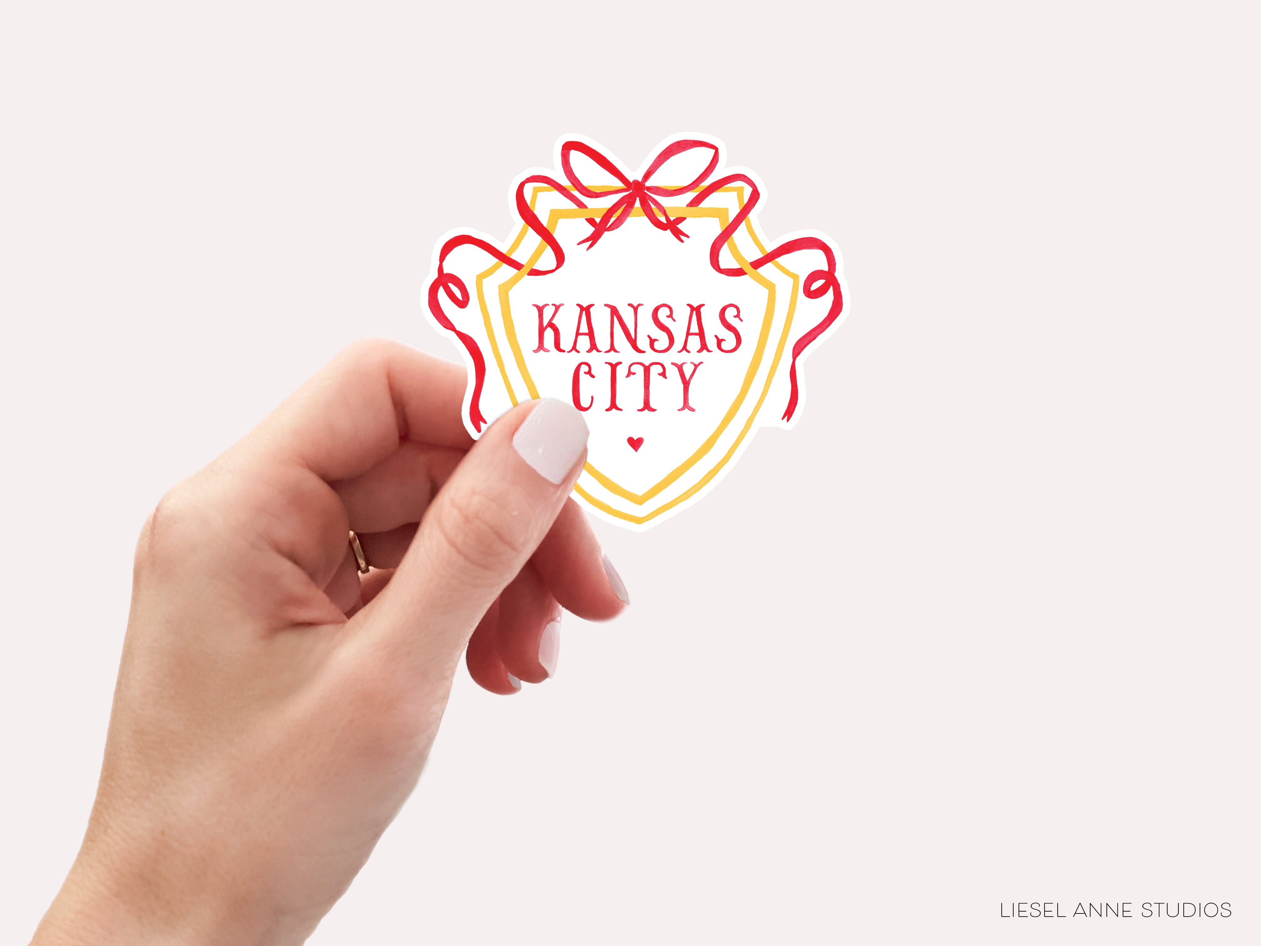 a hand holding a kansas city sticker in front of a white background