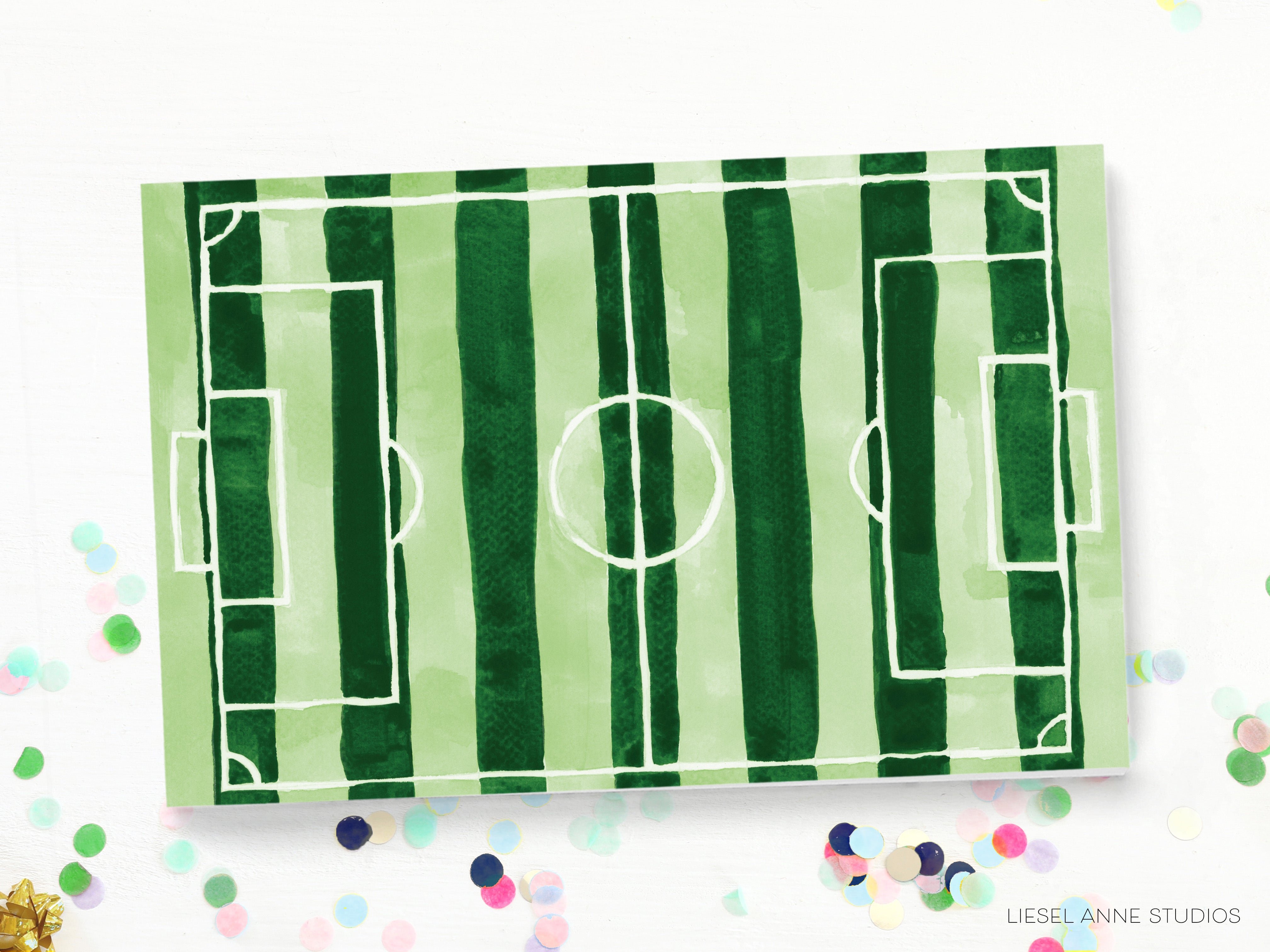 a green and white striped soccer field with a white circle in the center, surrounded by confetti.