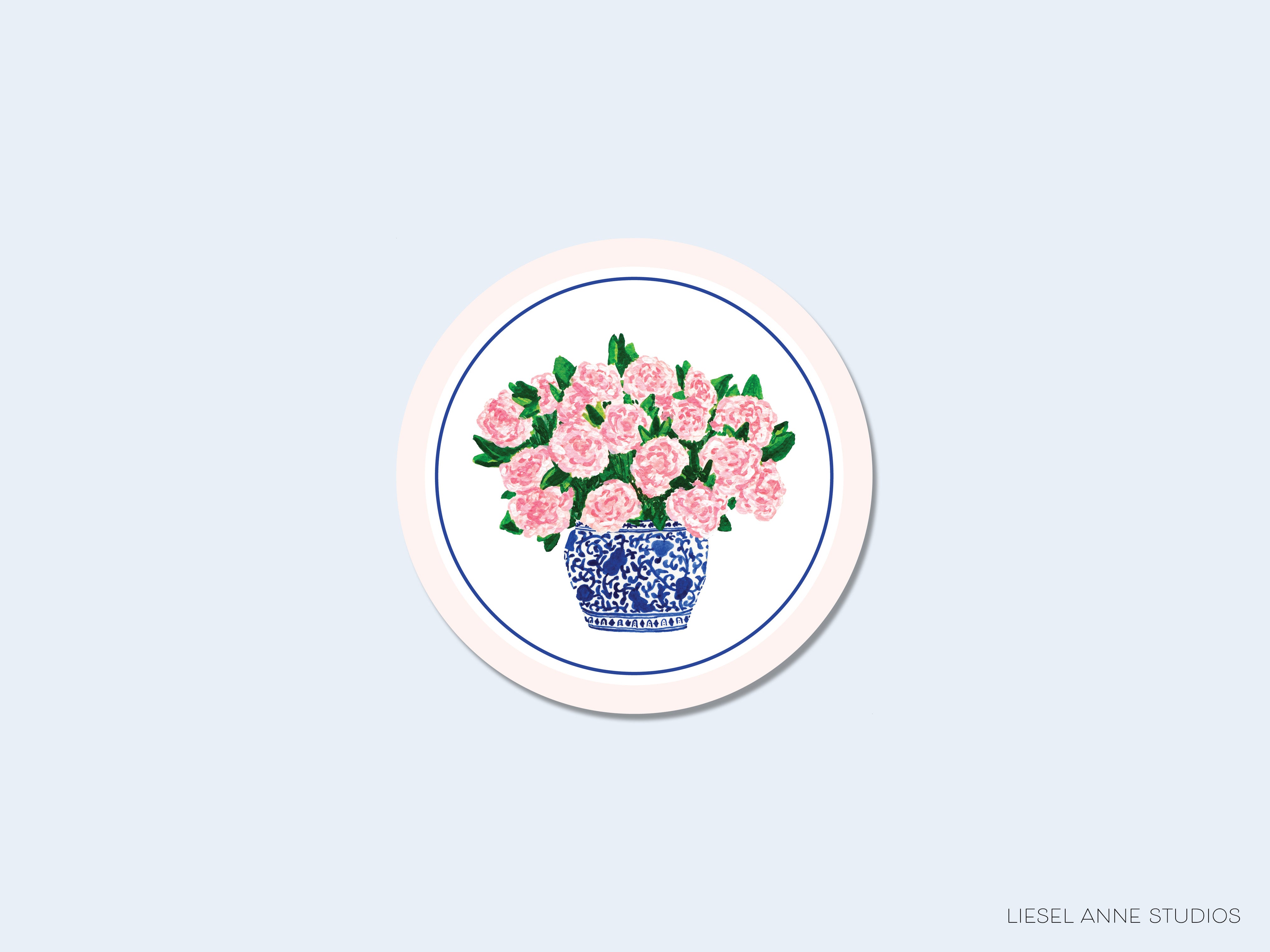 A round, white plate with a blue and white patterned vase containing pink flowers.
