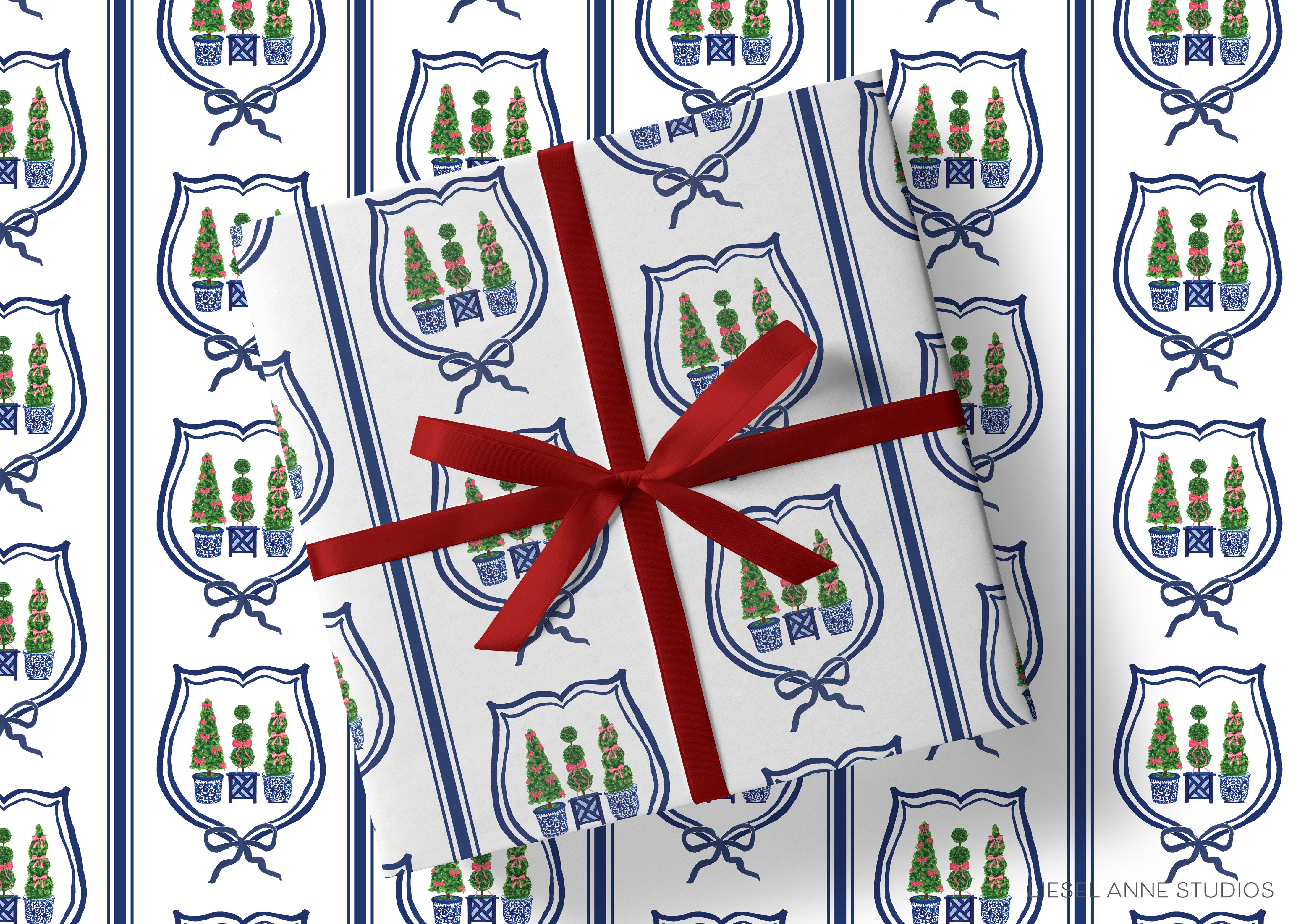 a gift wrapped in a white paper with a red ribbon, adorned with a repeating pattern of blue and green shields with white borders and red bows.