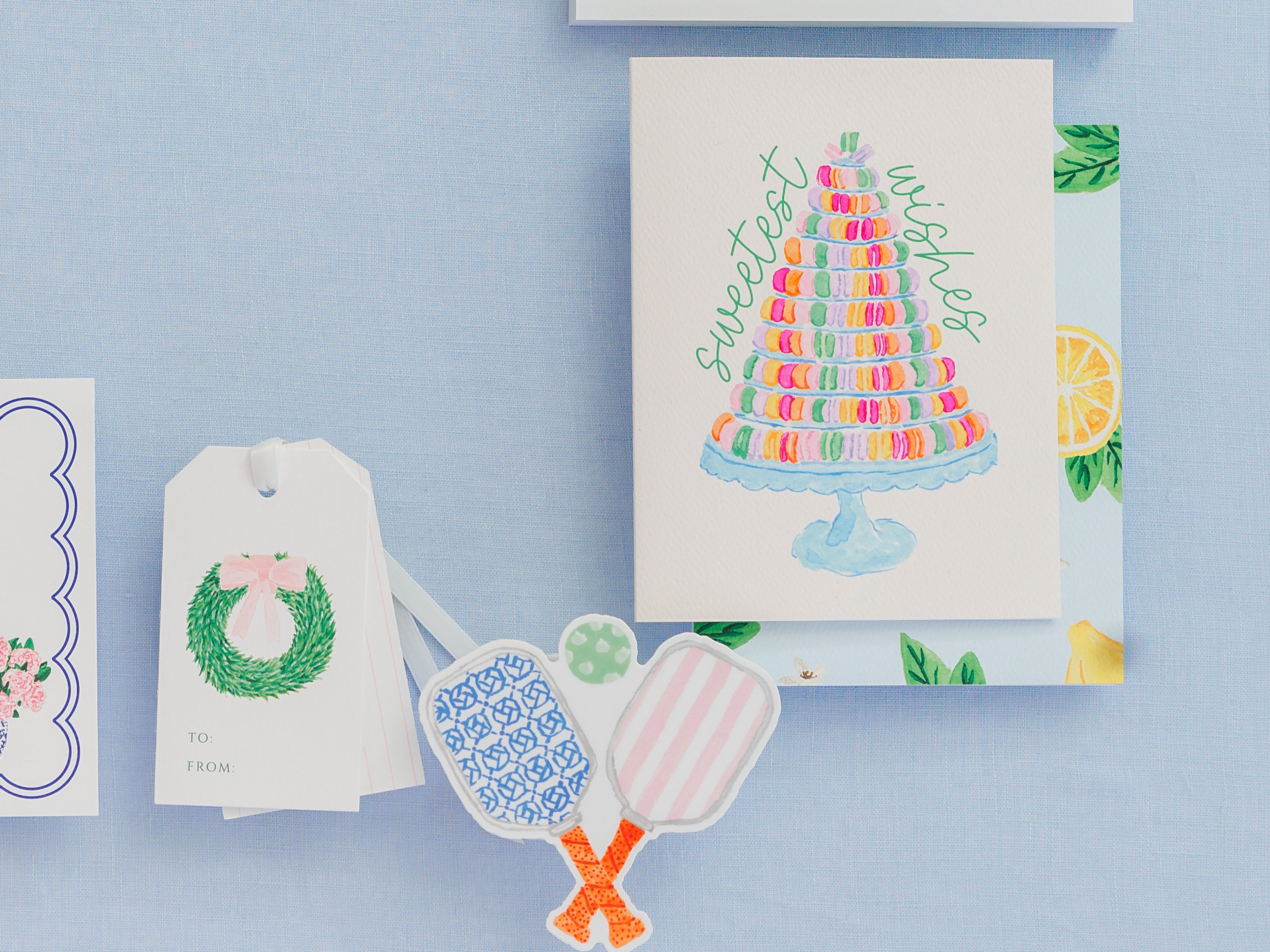a collection of decorative items, including a card with a cake illustration, a tag with a wreath design, and some colorful stickers.