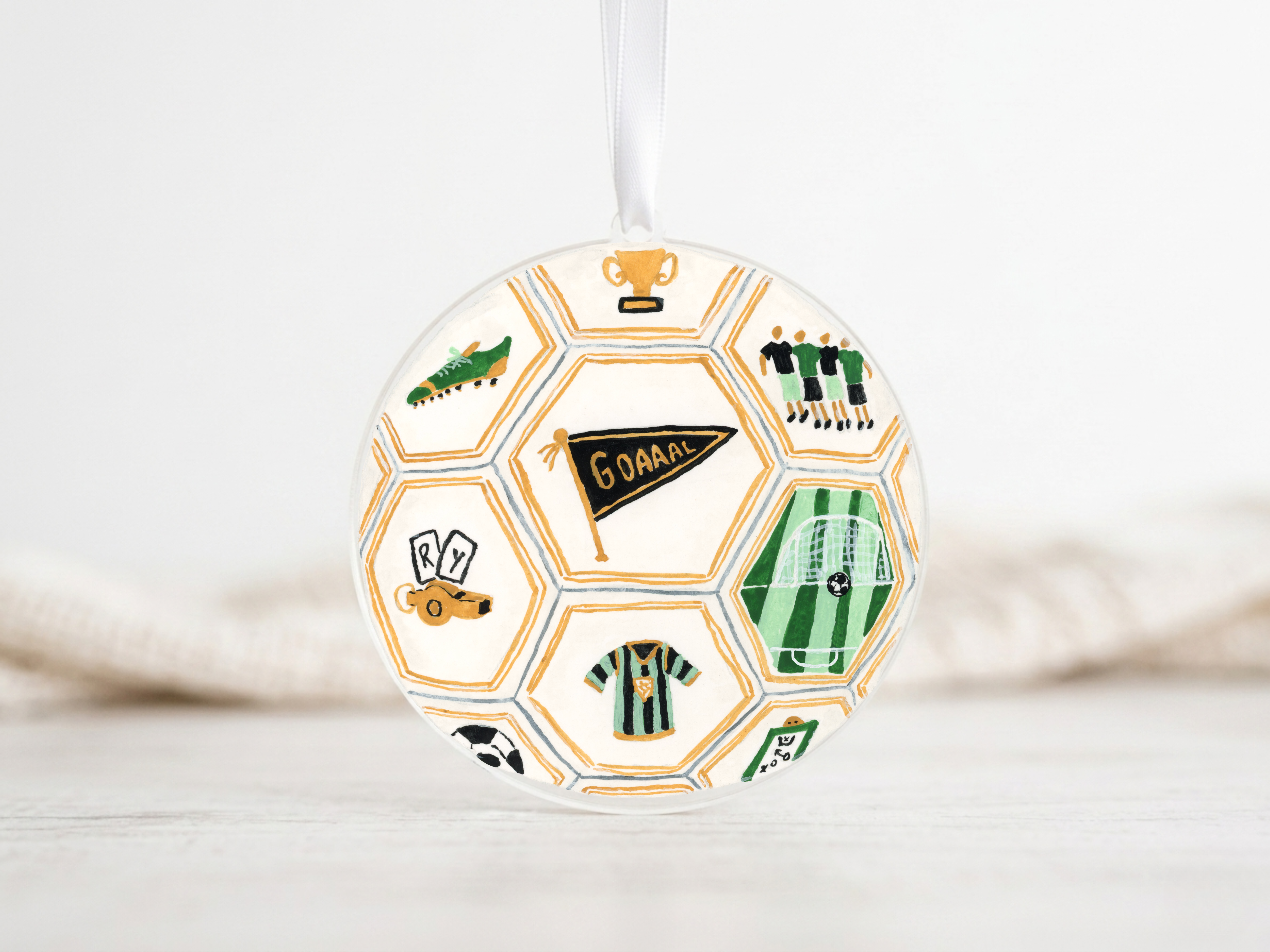 A round ornament with a soccer ball design, featuring various soccer-related icons and text.