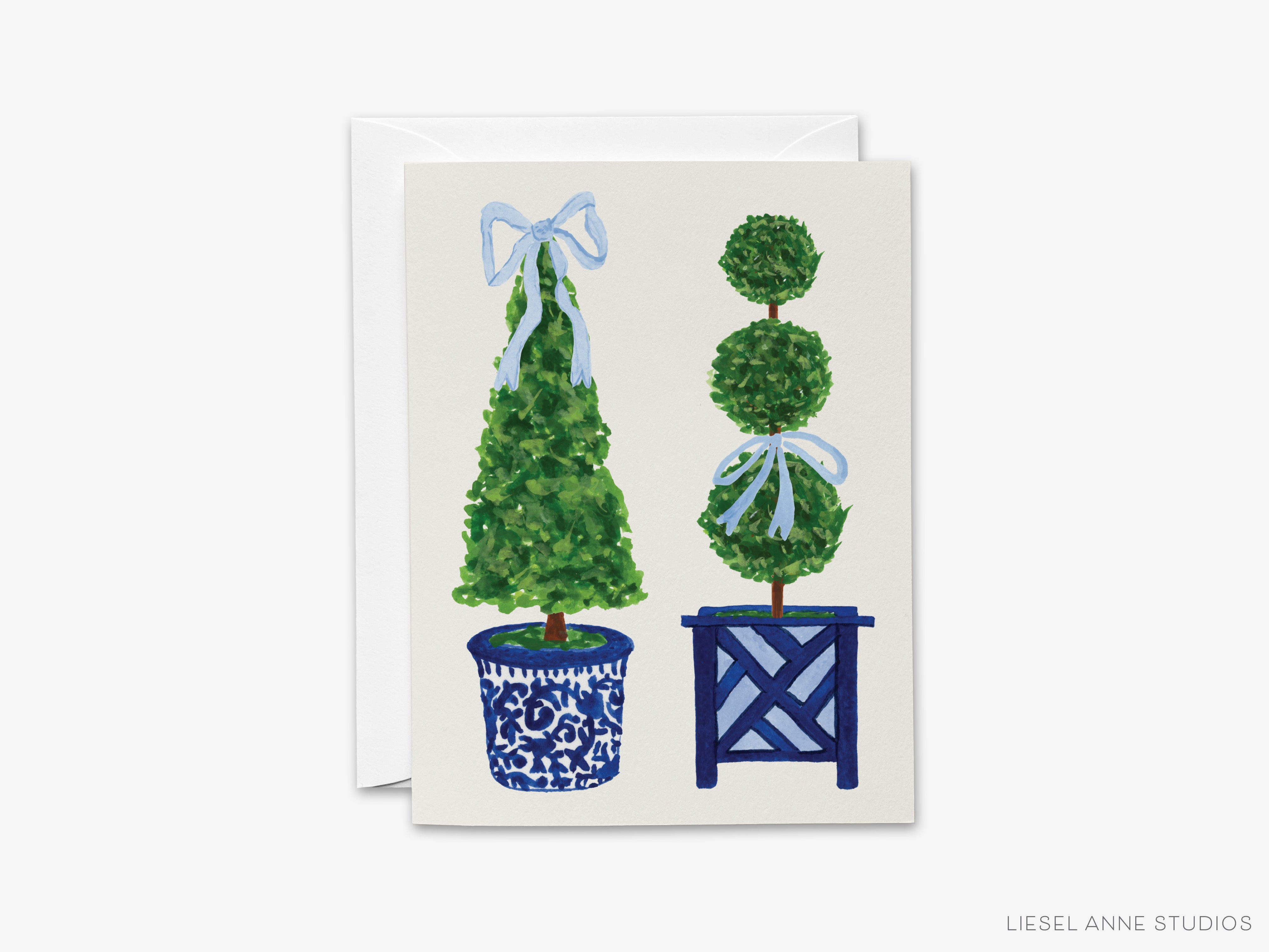 A greeting card featuring two topiary trees in blue and white vases, with a white envelope visible in the background.