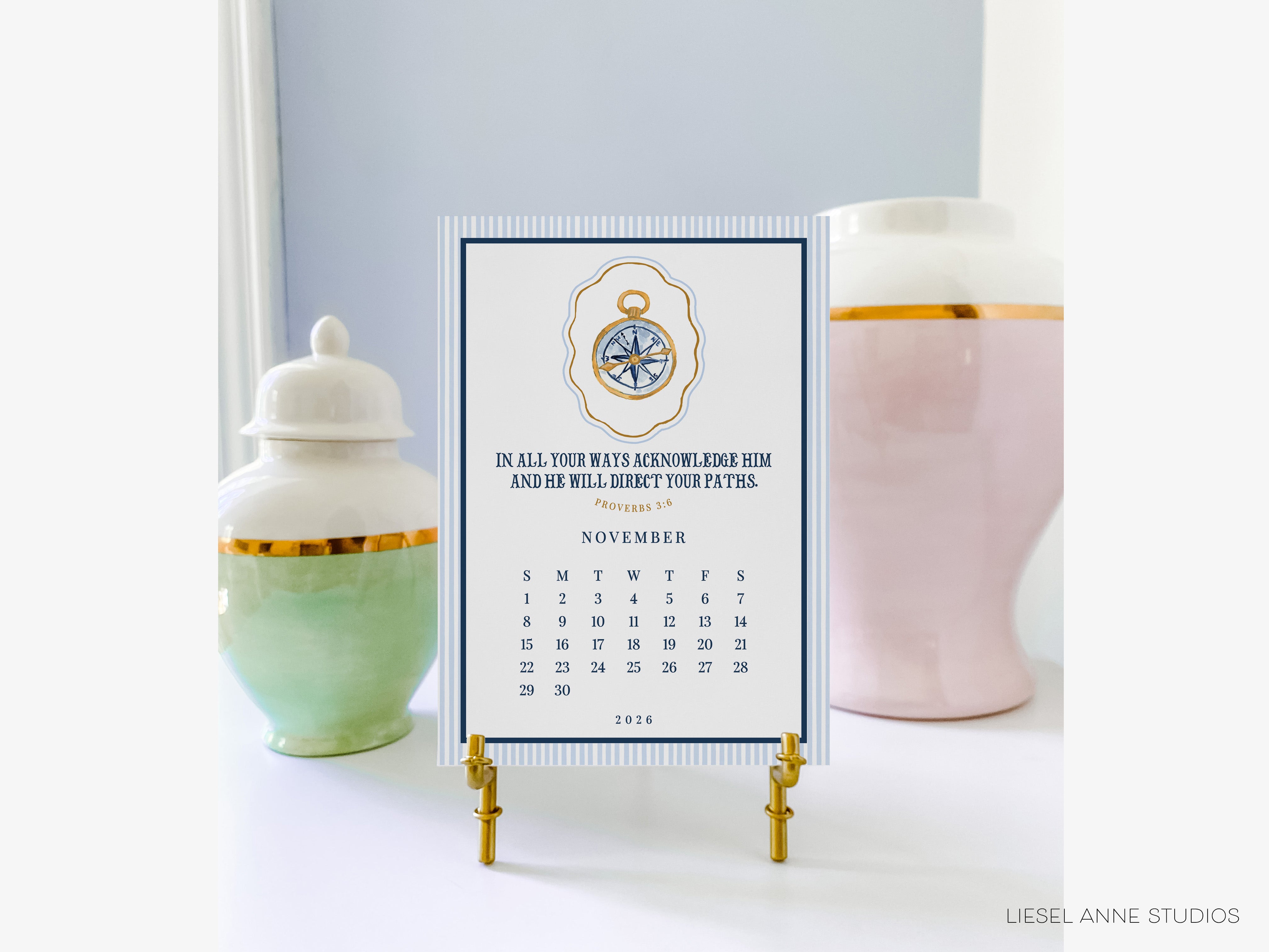 a calendar on a stand with a compass design, placed between two decorative vases.