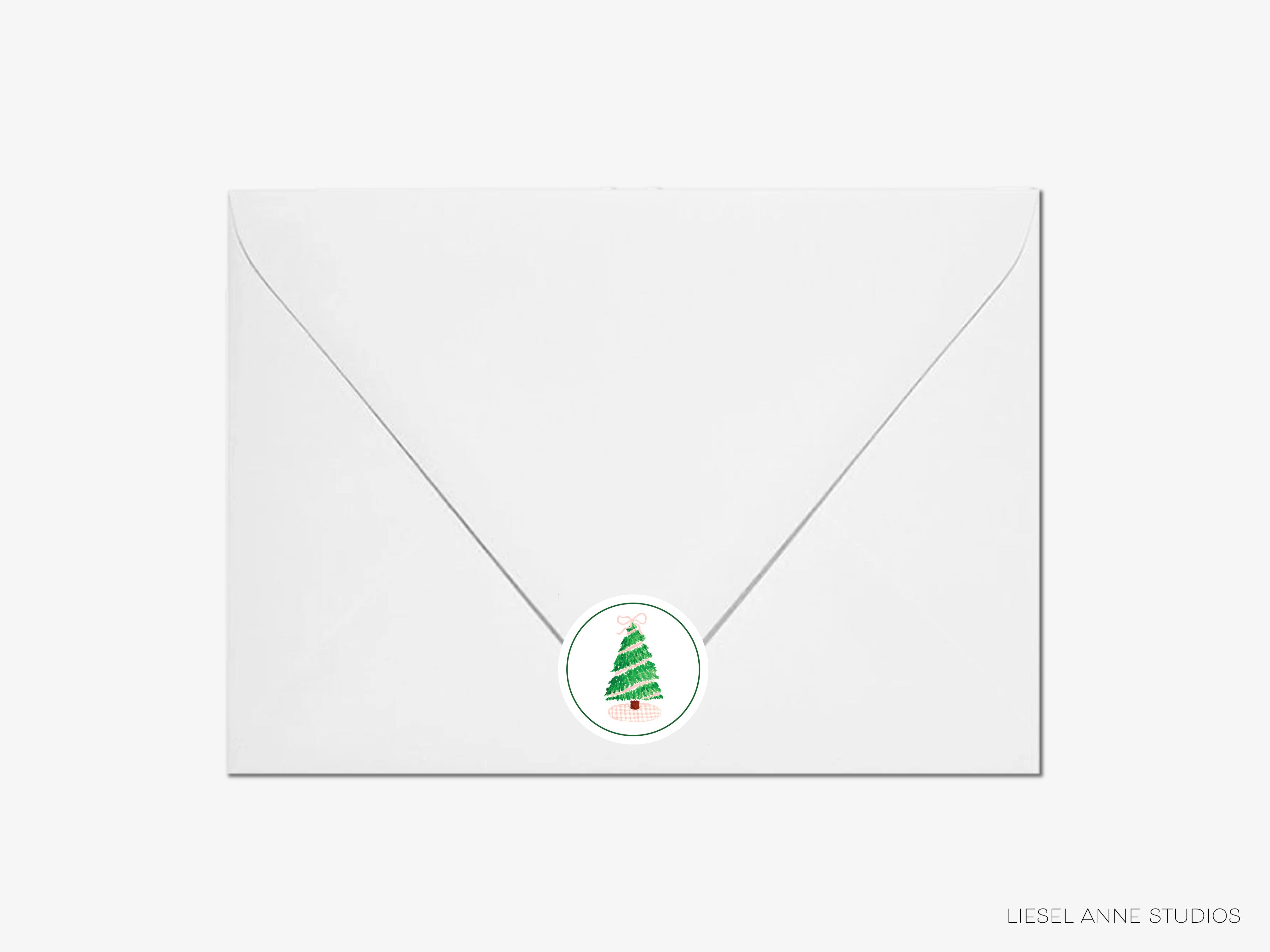 A white envelope with a circular Christmas tree sticker on it.