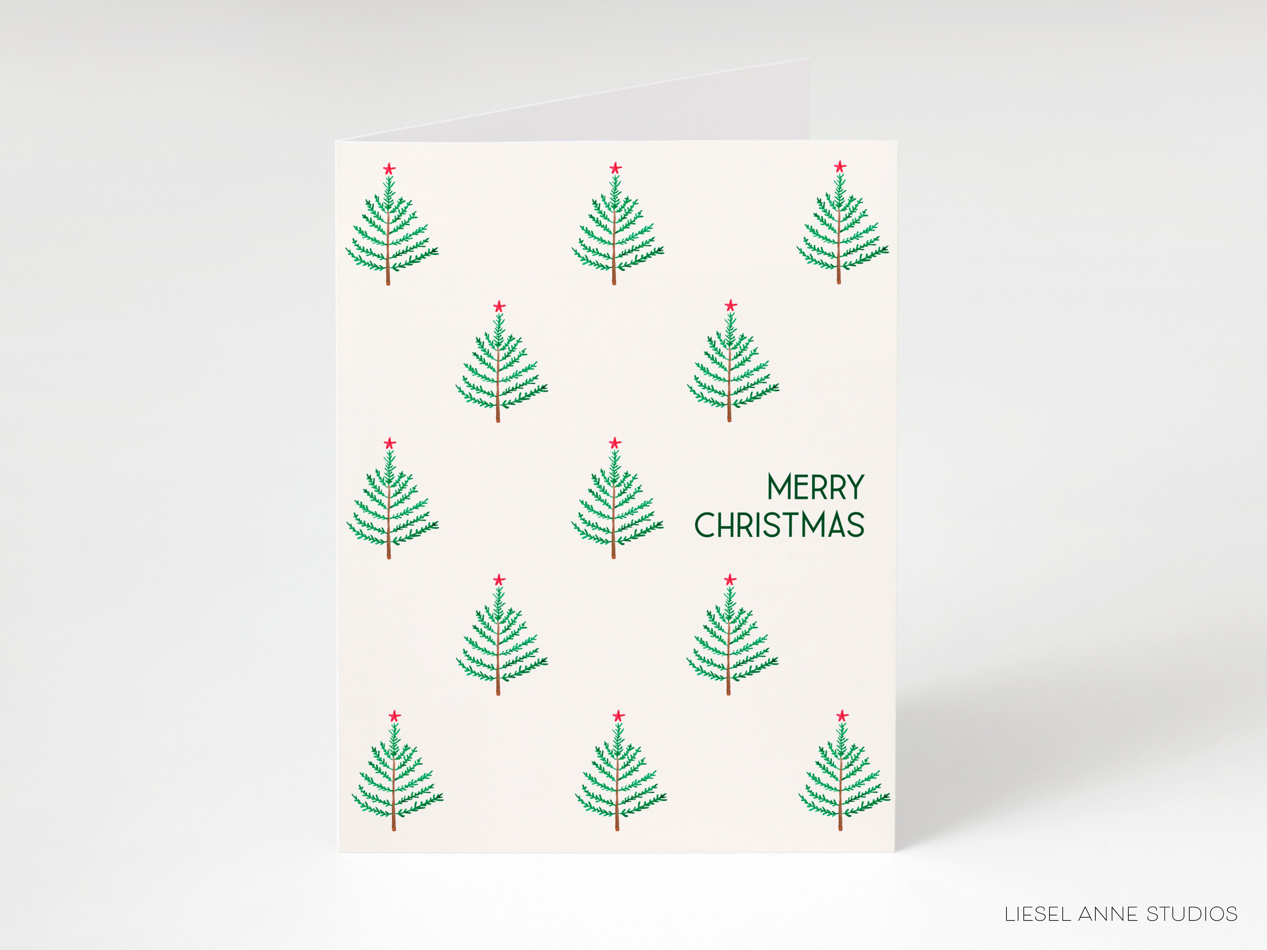 A Christmas card with a repeating pattern of small green Christmas trees with red ornaments on top, and the text "MERRY CHRISTMAS" written in green on the right side.