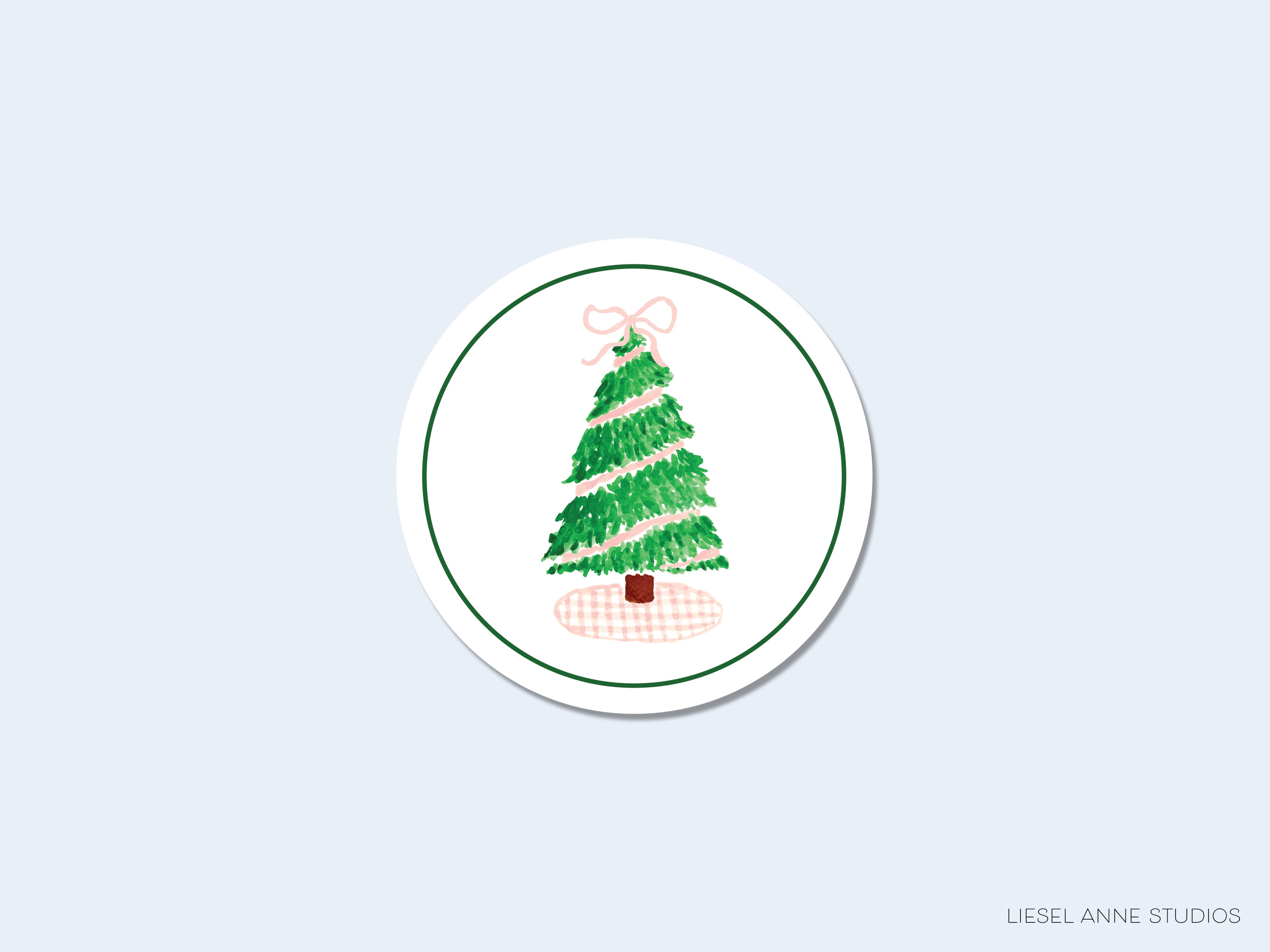 A white circular sticker with a green and pink Christmas tree illustration on it.