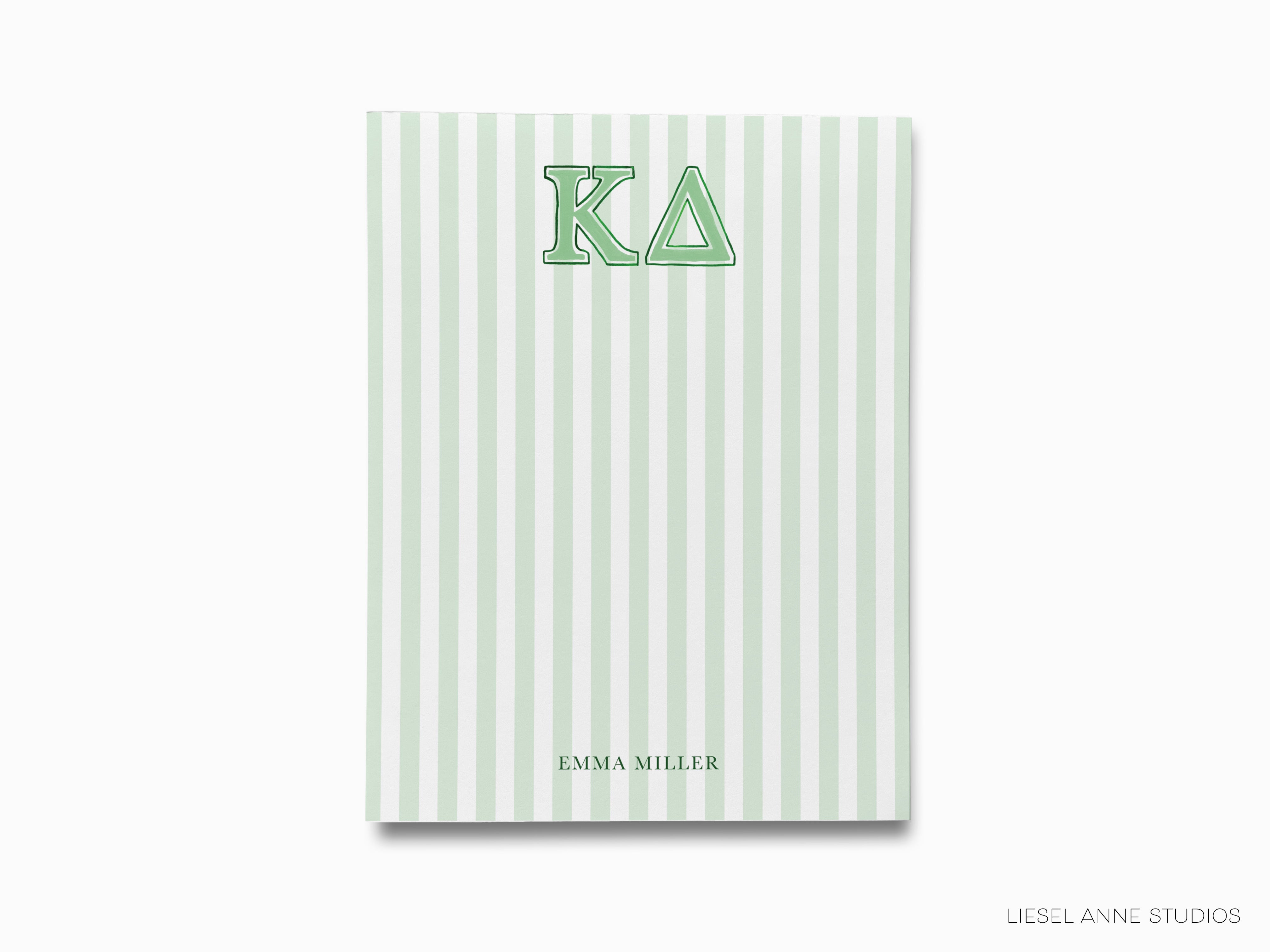 a green and white striped notebook with the letter k a on it
