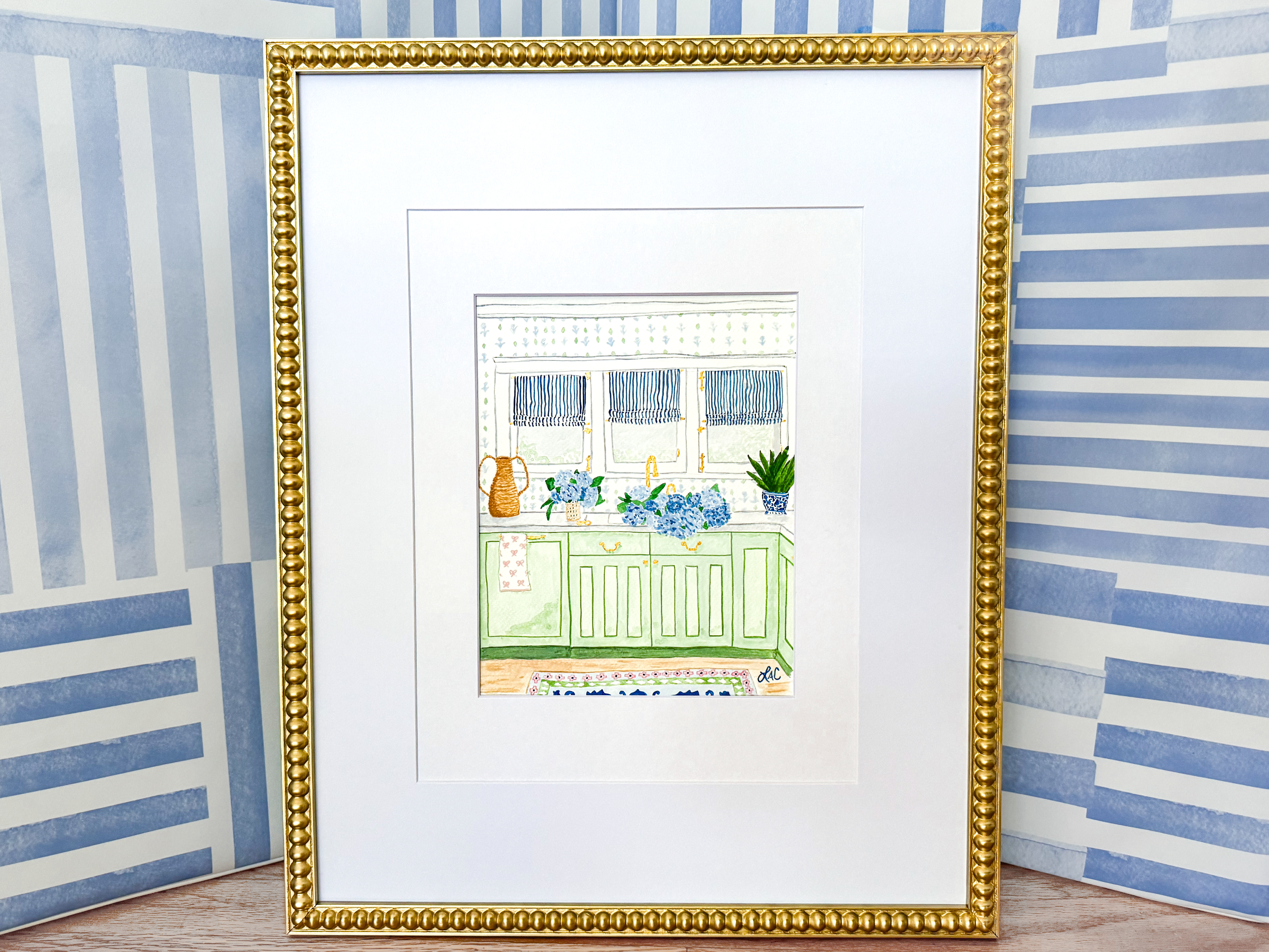 a framed illustration of a kitchen scene with a green cabinet, blue and white striped wall, and various decorative elements such as a vase and potted plant.