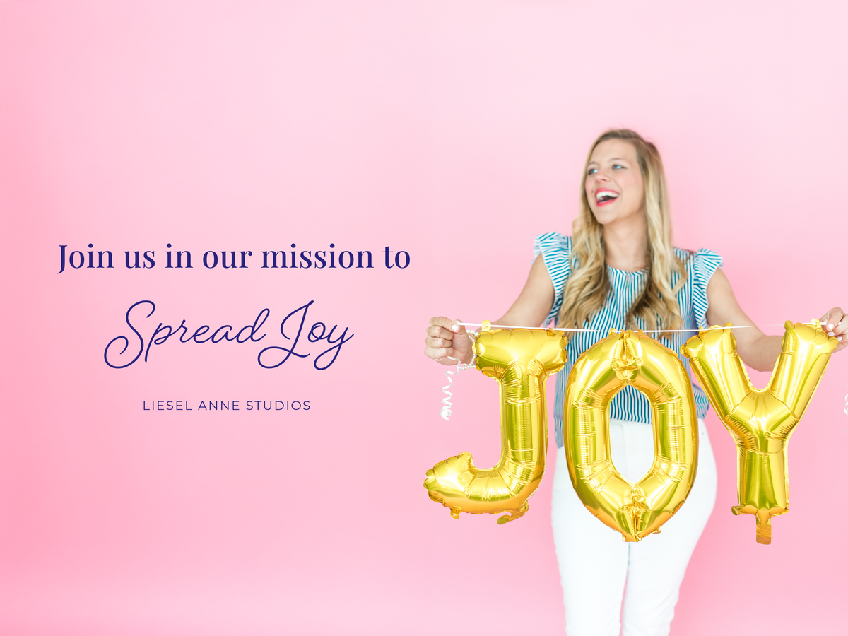 A woman holding large gold foil letters spelling "Joy" against a pink background.