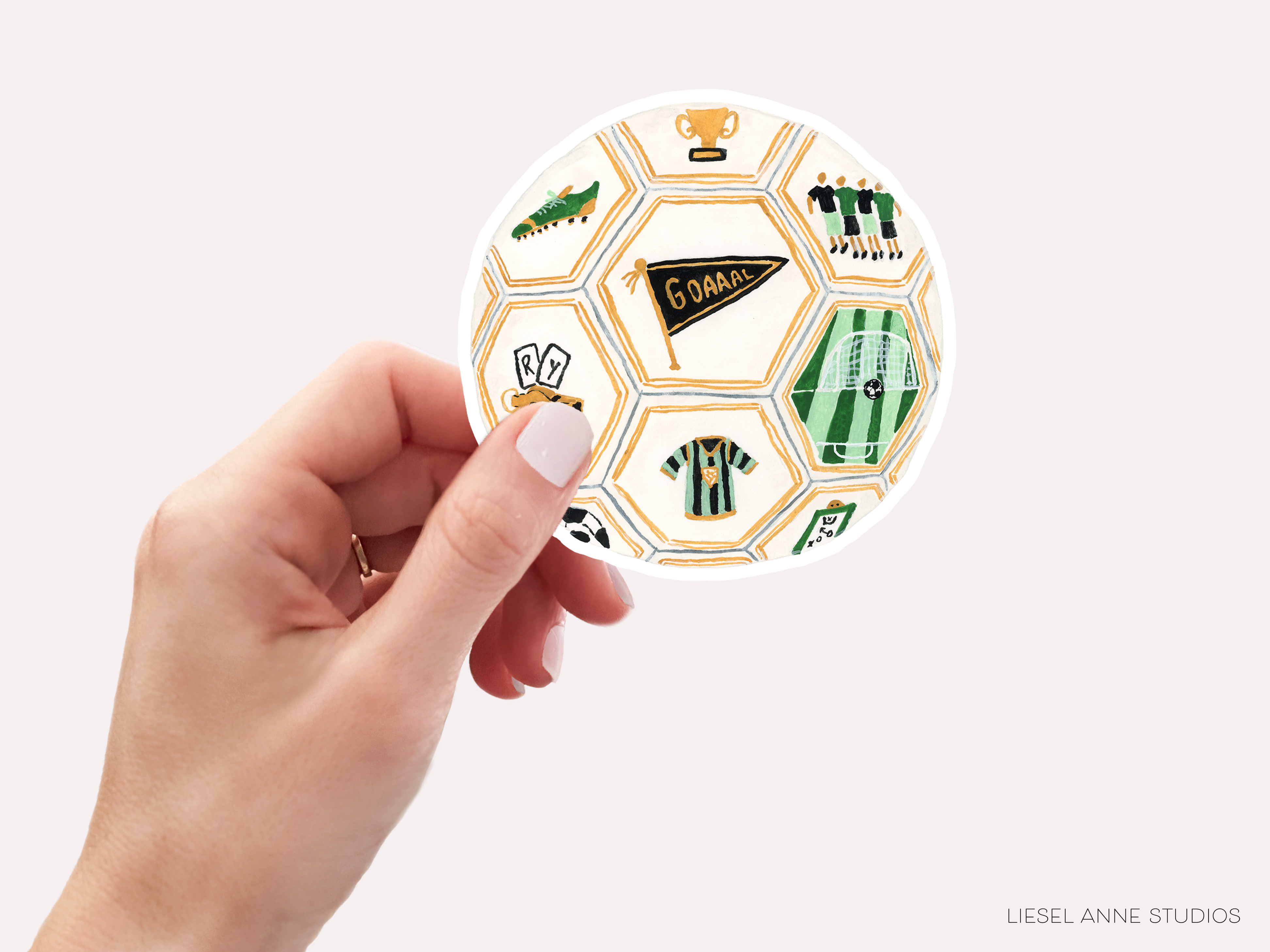 A hand holding a sticker with various soccer-related icons and text.