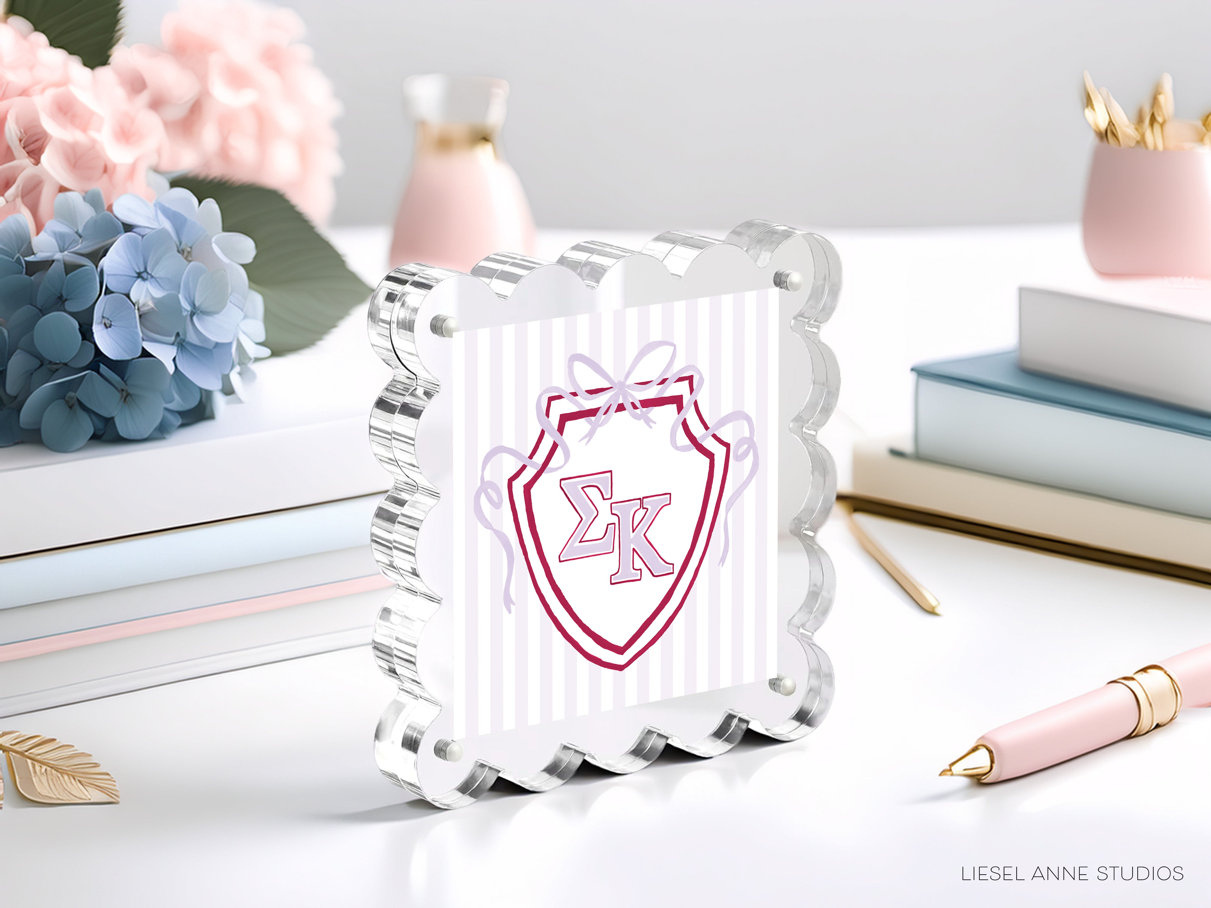 a clear glass frame with a decorative shield design, surrounded by various objects such as books, flowers, and a pen.