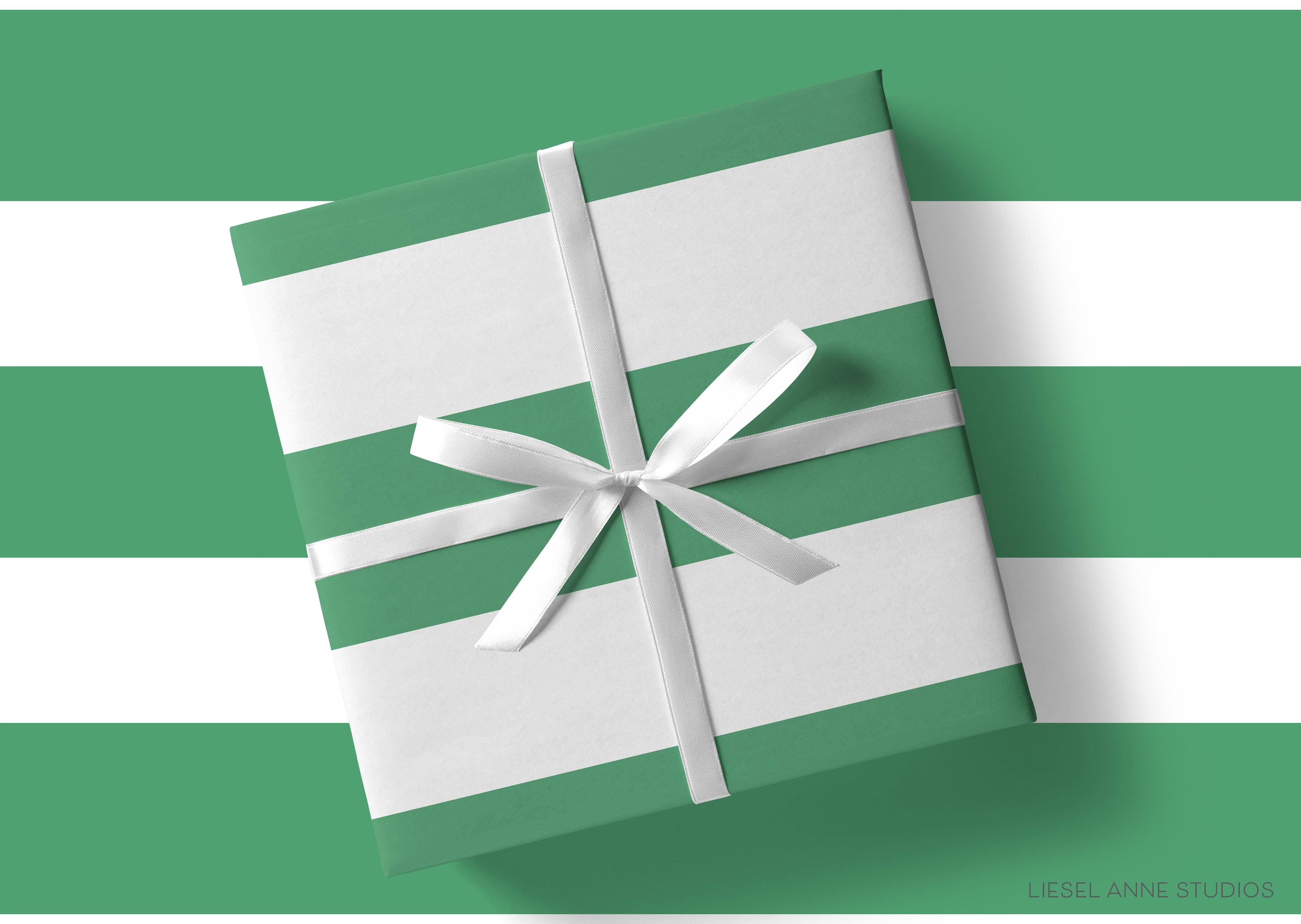 A gift wrapped in green and white paper with a white ribbon tied around it, placed on a green and white striped background.