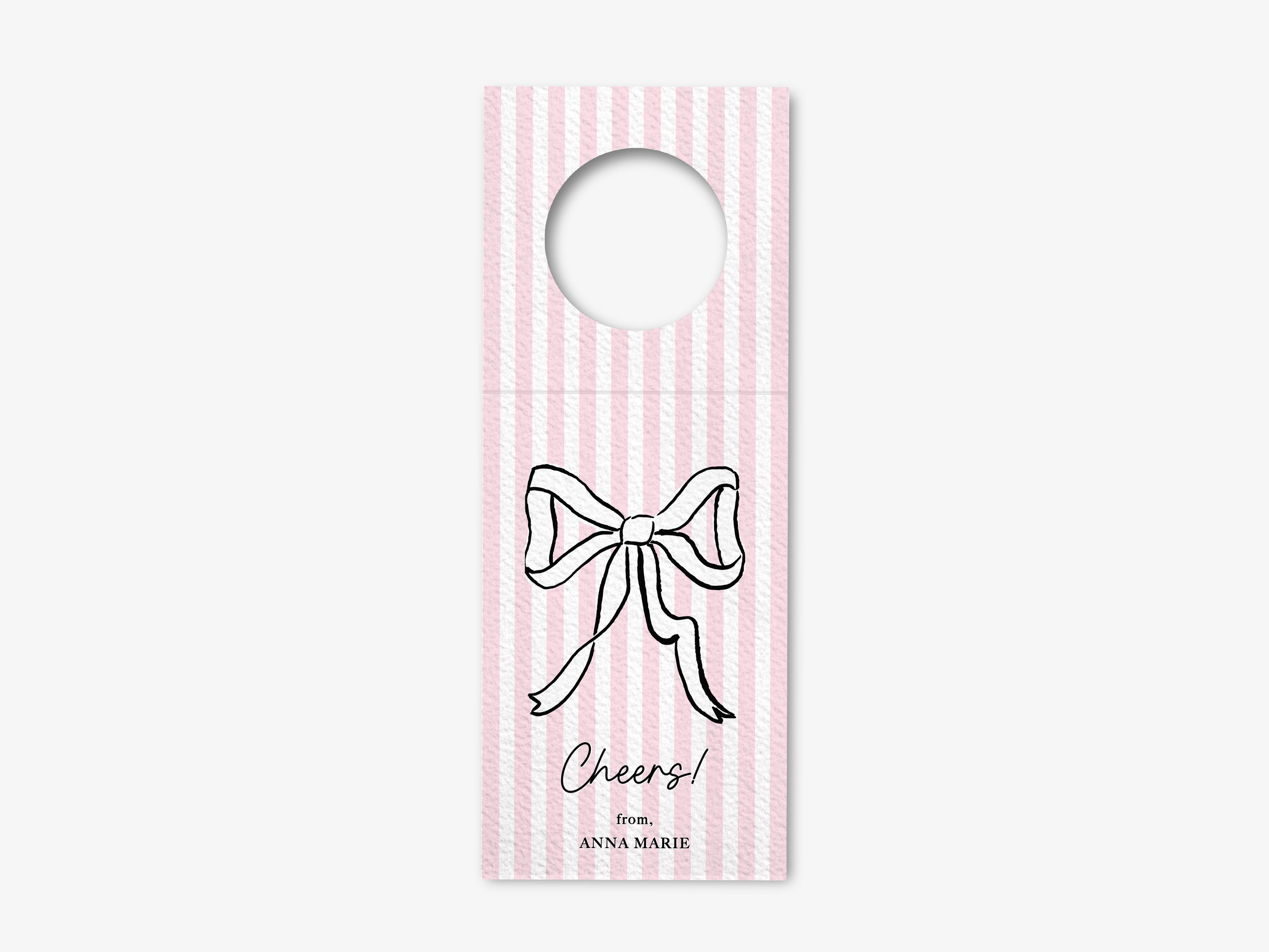 A pink and white striped door hanger with a bow and the text "Cheers!" printed on it.