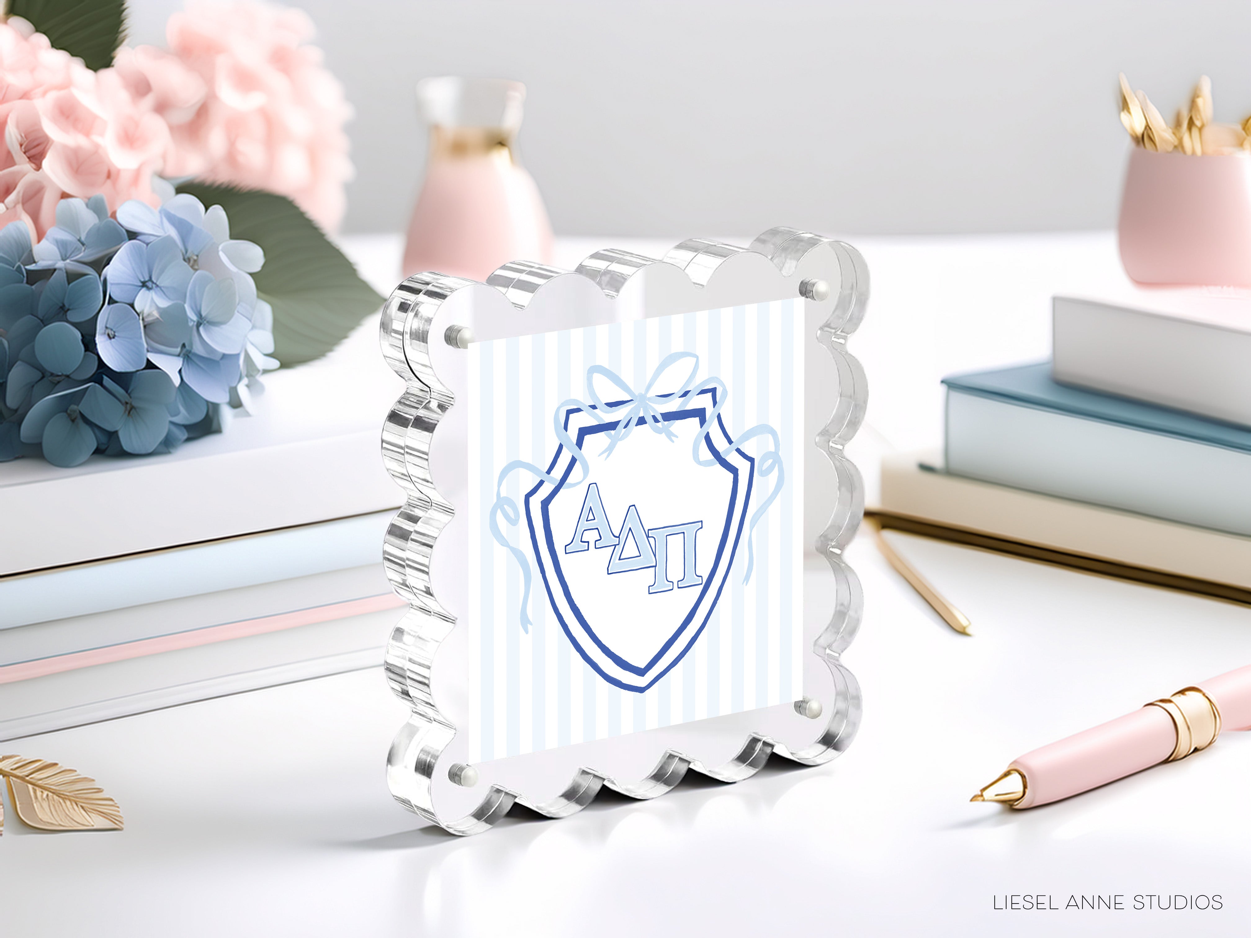 a clear glass frame with a blue and white shield design, surrounded by various objects such as books, flowers, and a pen.