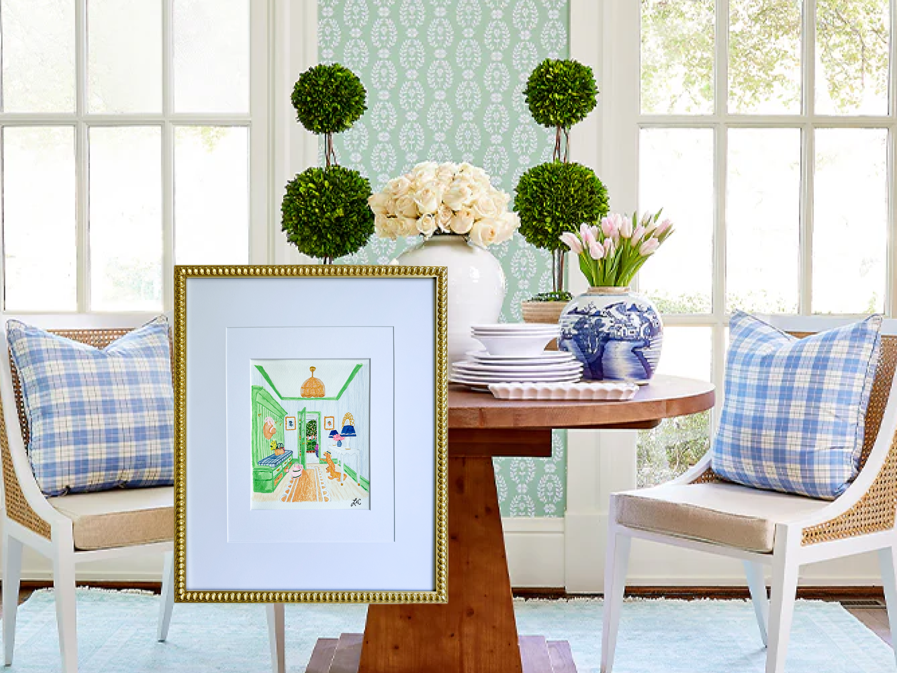 a cozy and well-decorated dining area with a wooden table, two chairs, and a framed picture on the wall. The table is adorned with a vase of flowers, a blue and white china plate, and a stack of white plates. The chairs have blue and white plaid pillows. The overall scene conveys a sense of warmth and comfort, with the framed picture adding an artistic touch to the space.