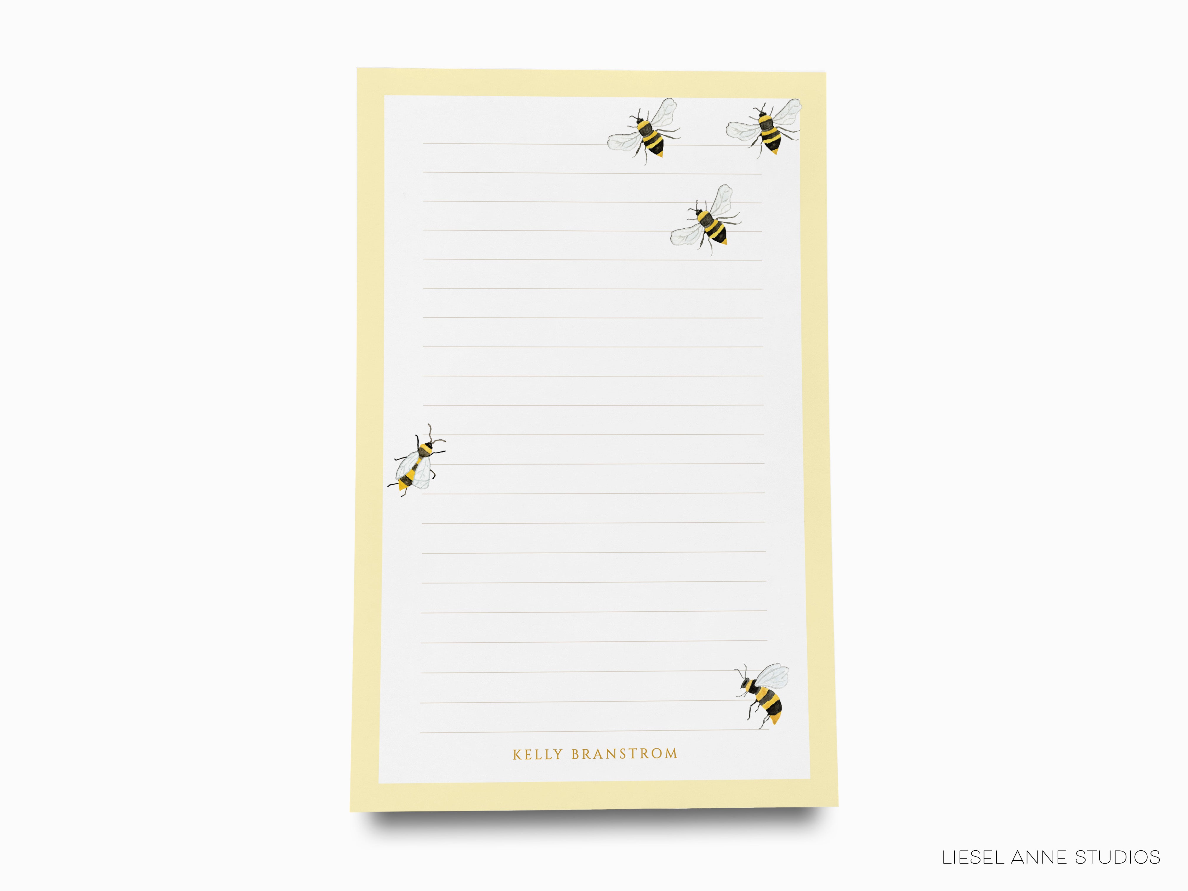 a yellow lined paper pad with a playful design of four bees on it.