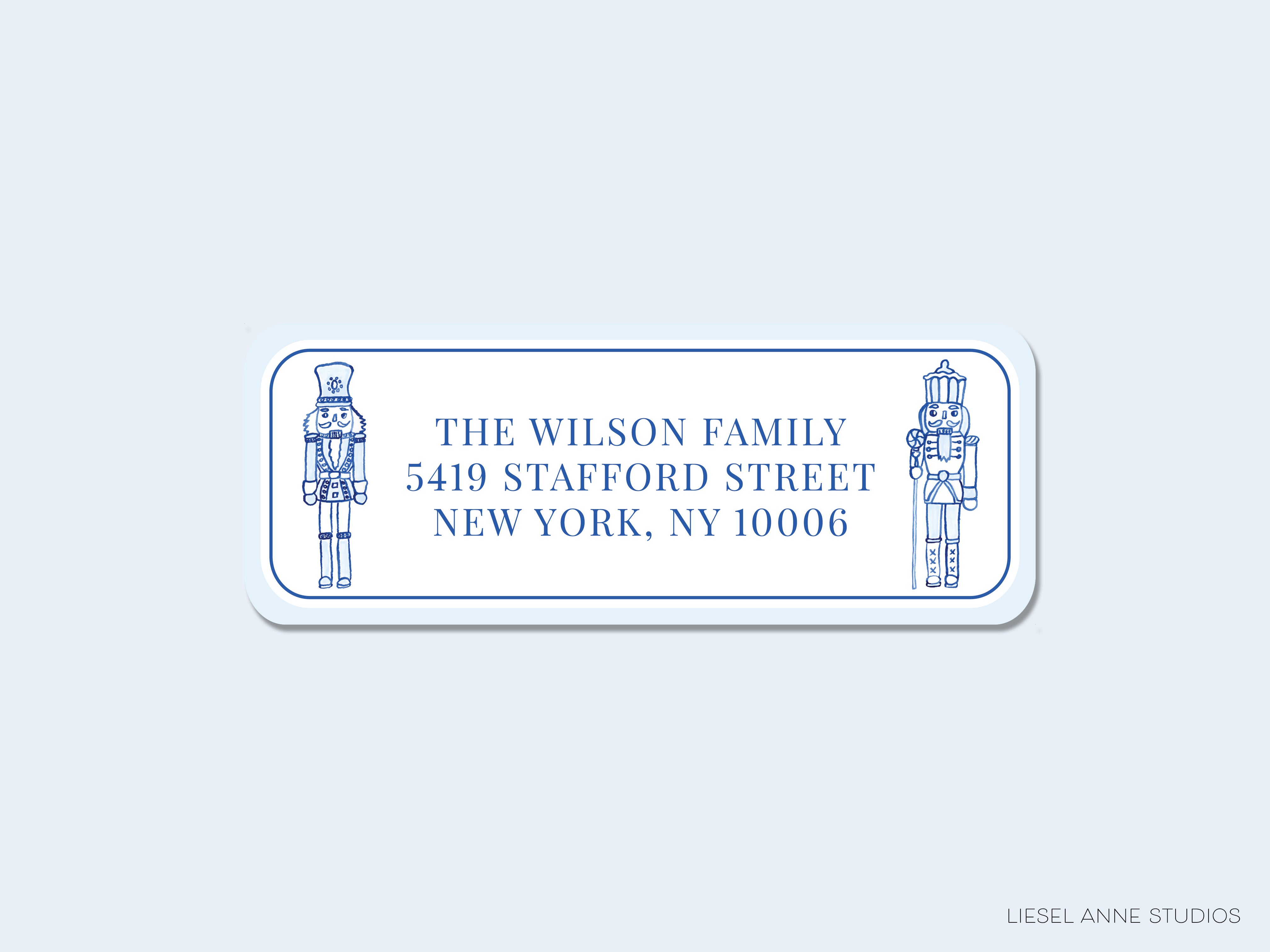 The image is a rectangular address label with blue text and illustrations of nutcracker figures.