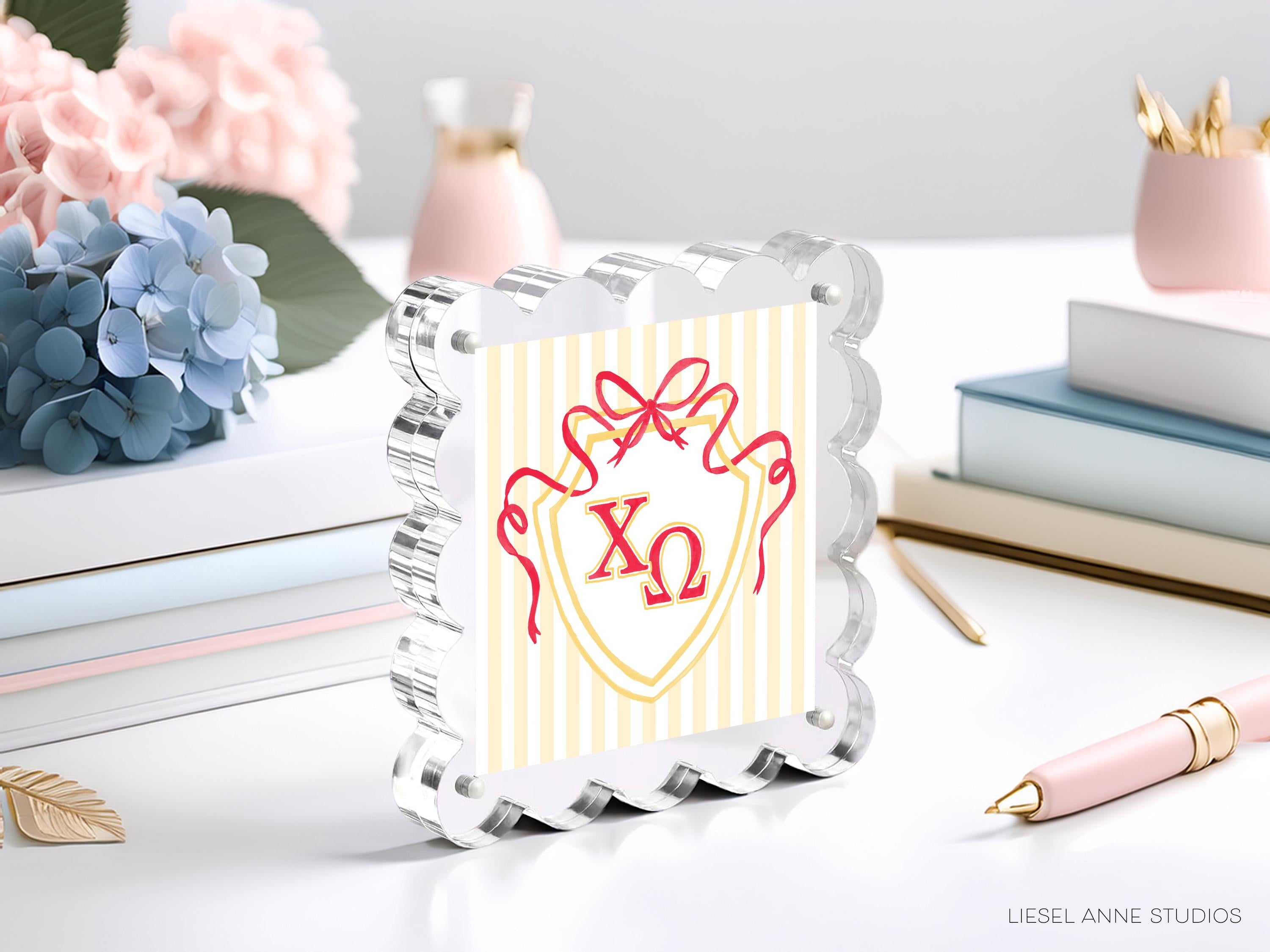 a clear glass frame with a decorative design, surrounded by various objects such as books, flowers, and a pen.